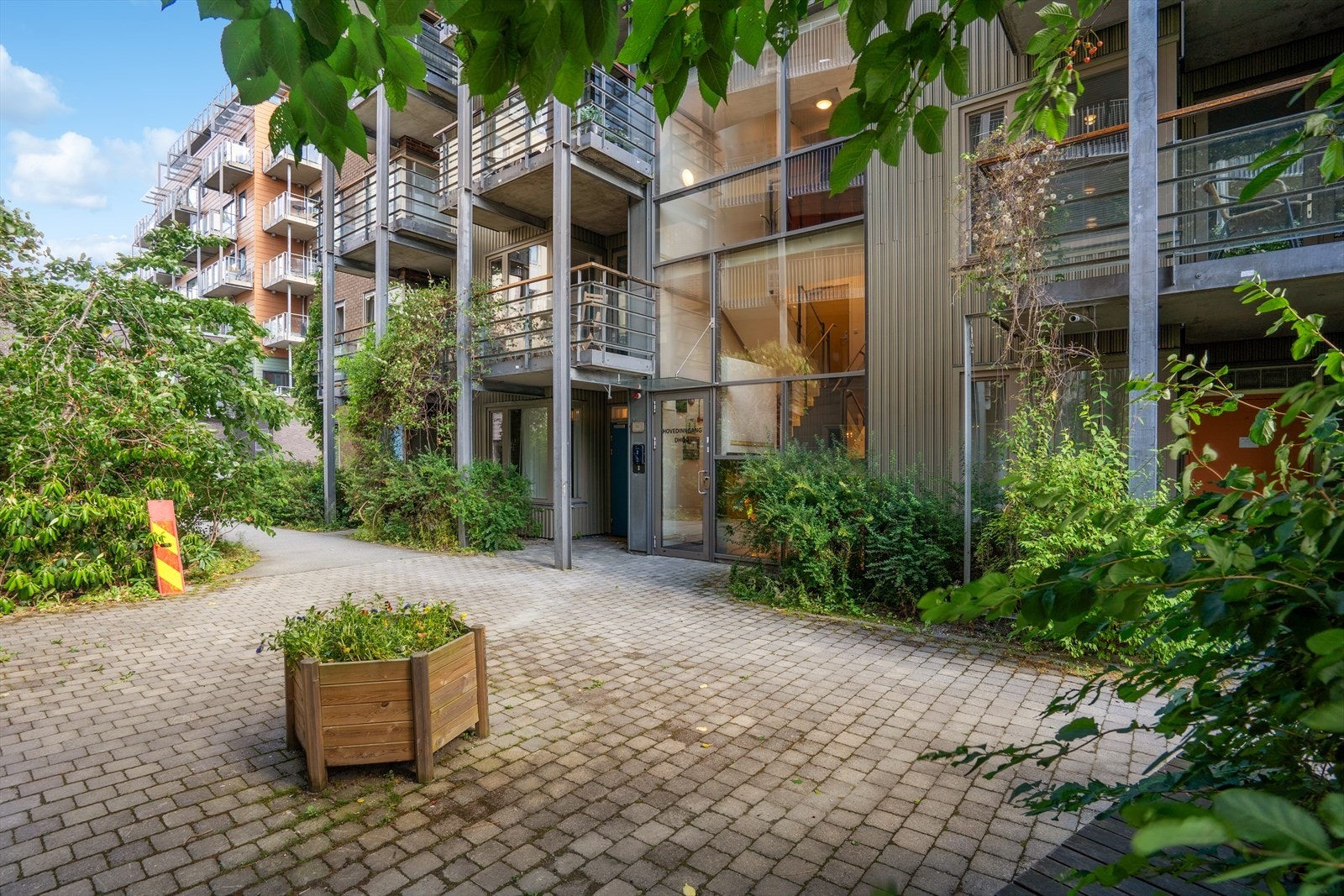 Velkommen hjem - et innbydende inngangsparti omkranset av frodig natur og harmonisk design. Her møtes estetikk og ro i perfekt balanse. Galleribilde