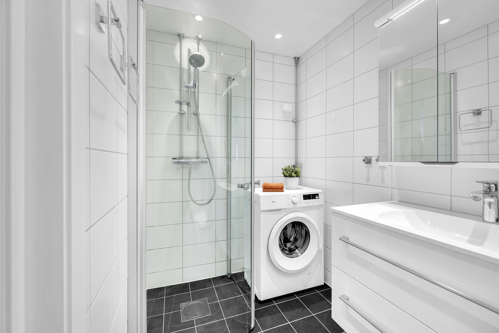 Det har flislagt gulv med behagelig gulvvarme, og er innredet med vegghengt toalett, dusjnisje med glassdører, samt servant med armatur integrert i praktisk baderomsinnredningen. Galleribilde