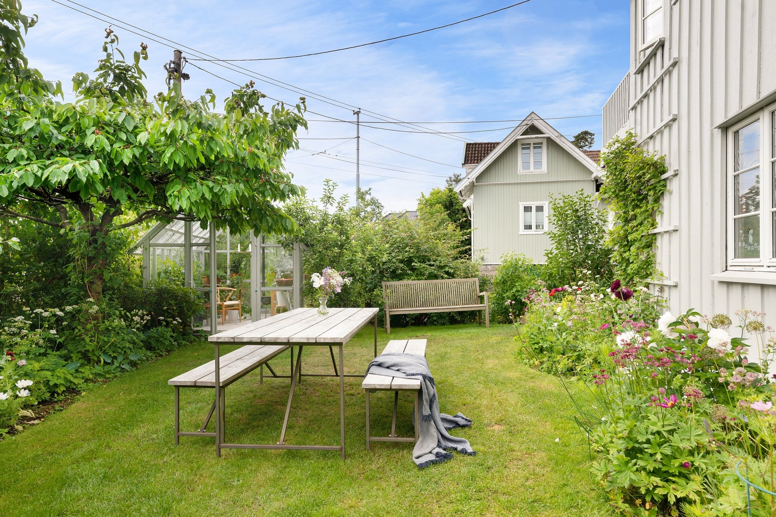Tomten er opparbeidet med frodig plen, drivhus, vakre planter, busker og frukttrær som gir både sjarm og trivsel. Galleribilde