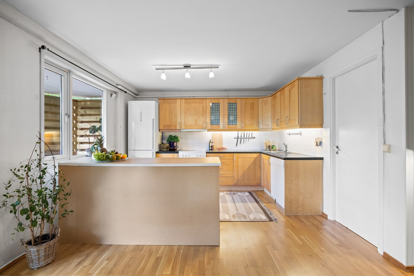 Kjøkkenet har en praktisk innredning med profilerte trefronter og laminat benkeplate med nedfelt kum i rustfritt stål. Galleribilde