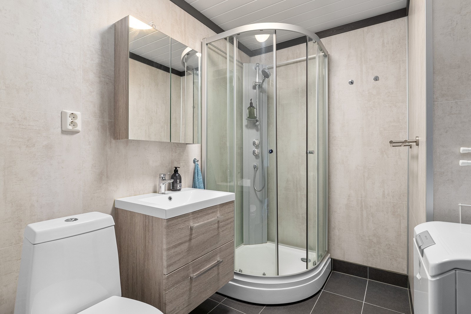 Pent og stilrent bad med flislagt gulv med varmekabler innredning og opplegg til vaskemaskin Galleribilde