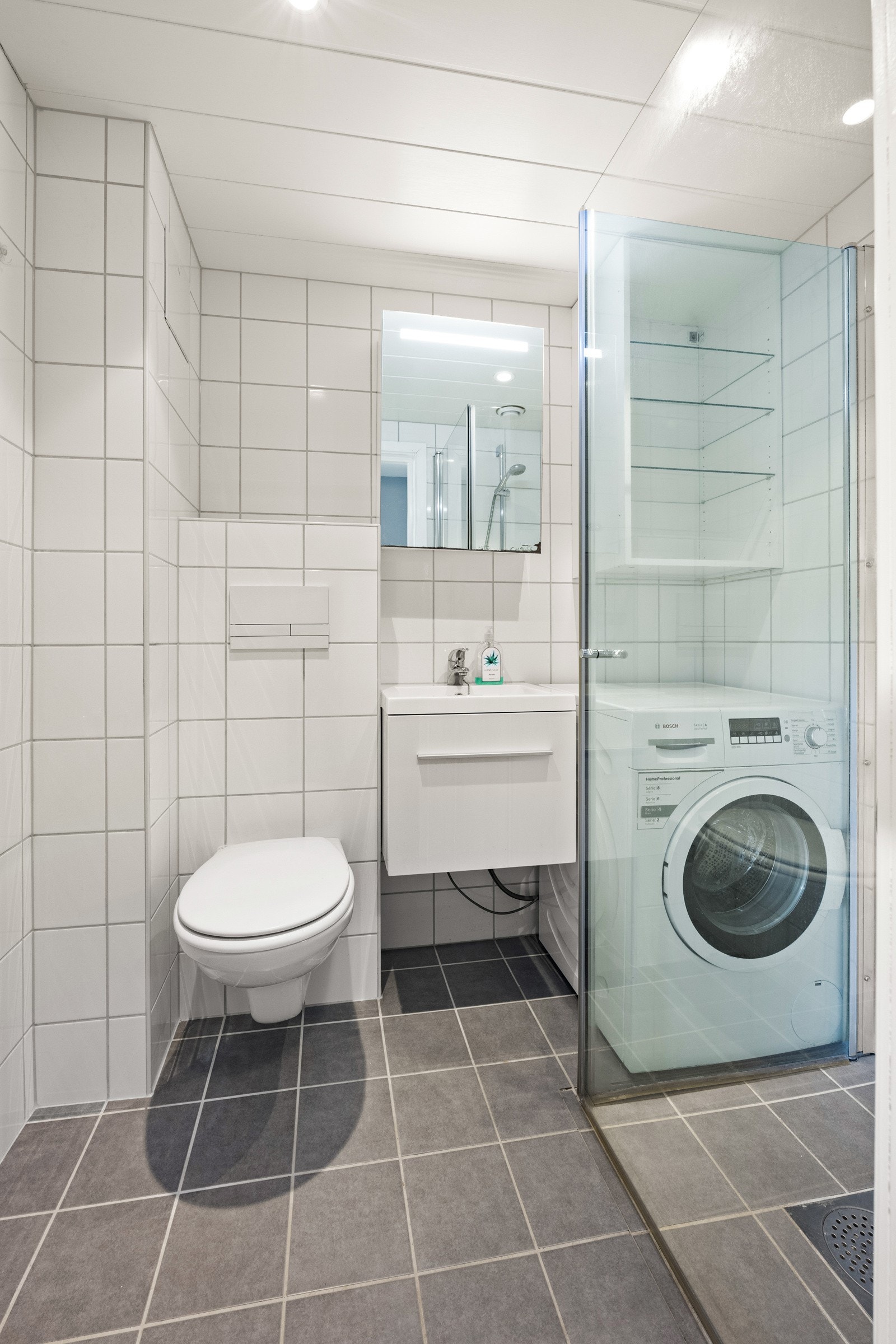 Pent flislagt bad med dusjhjørne og opplegg for vaskemaskin. Galleribilde