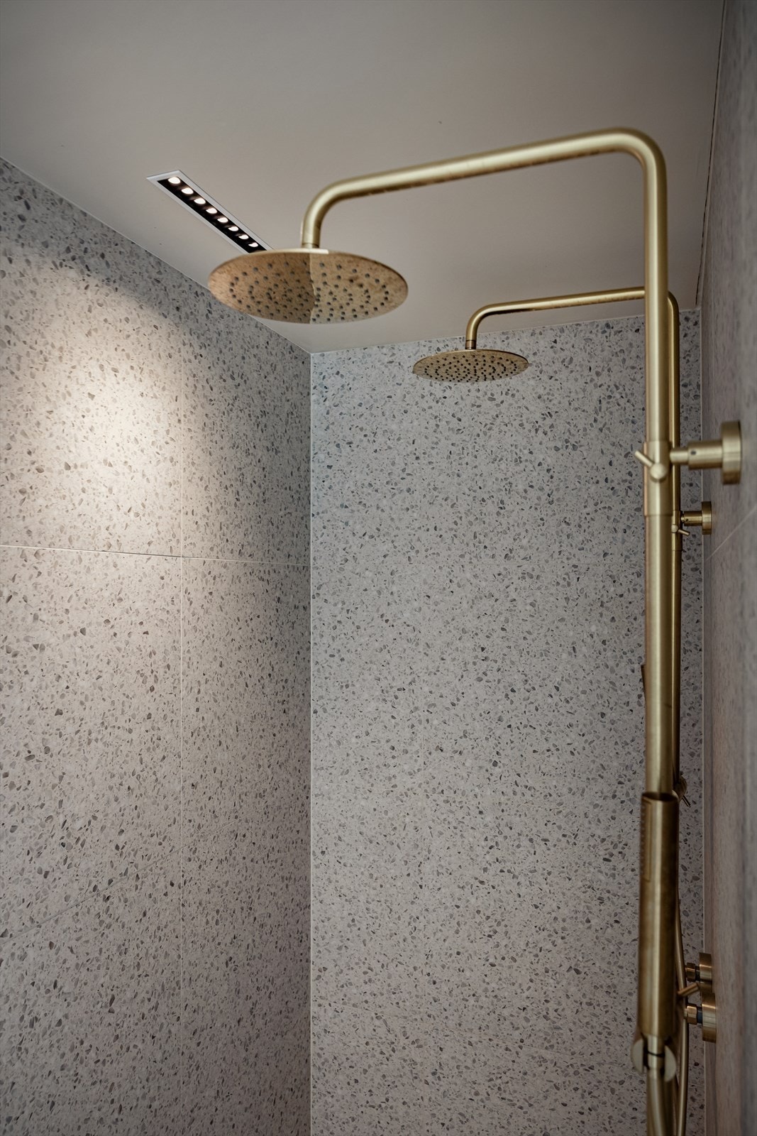 Baderommet har dusjnisje med dobbel dusjgarnityr på vegg og glassdør Galleribilde