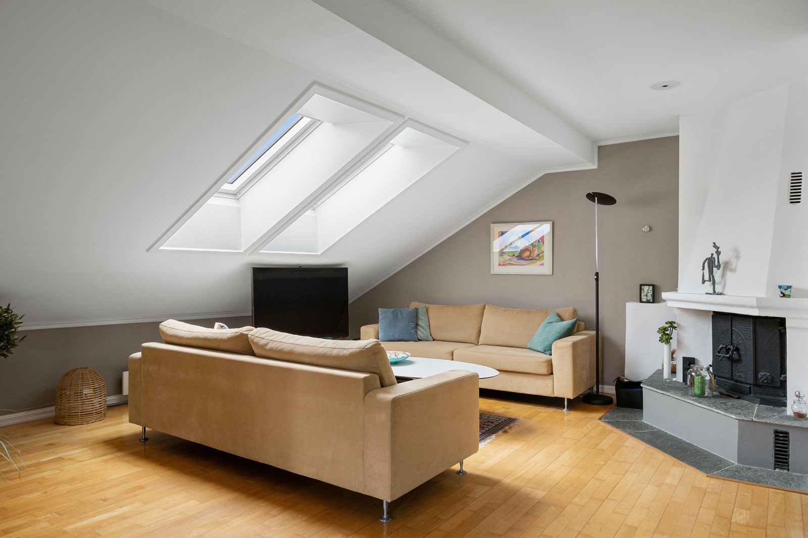 Veggoverflatene er stilrent dekorert med lyse fargetoner og gulvet er belagt med parkett. Legg også merke til rommets klassiske hjørnepeis som vil bidra med lun stemning i vinterhalvåret. Galleribilde