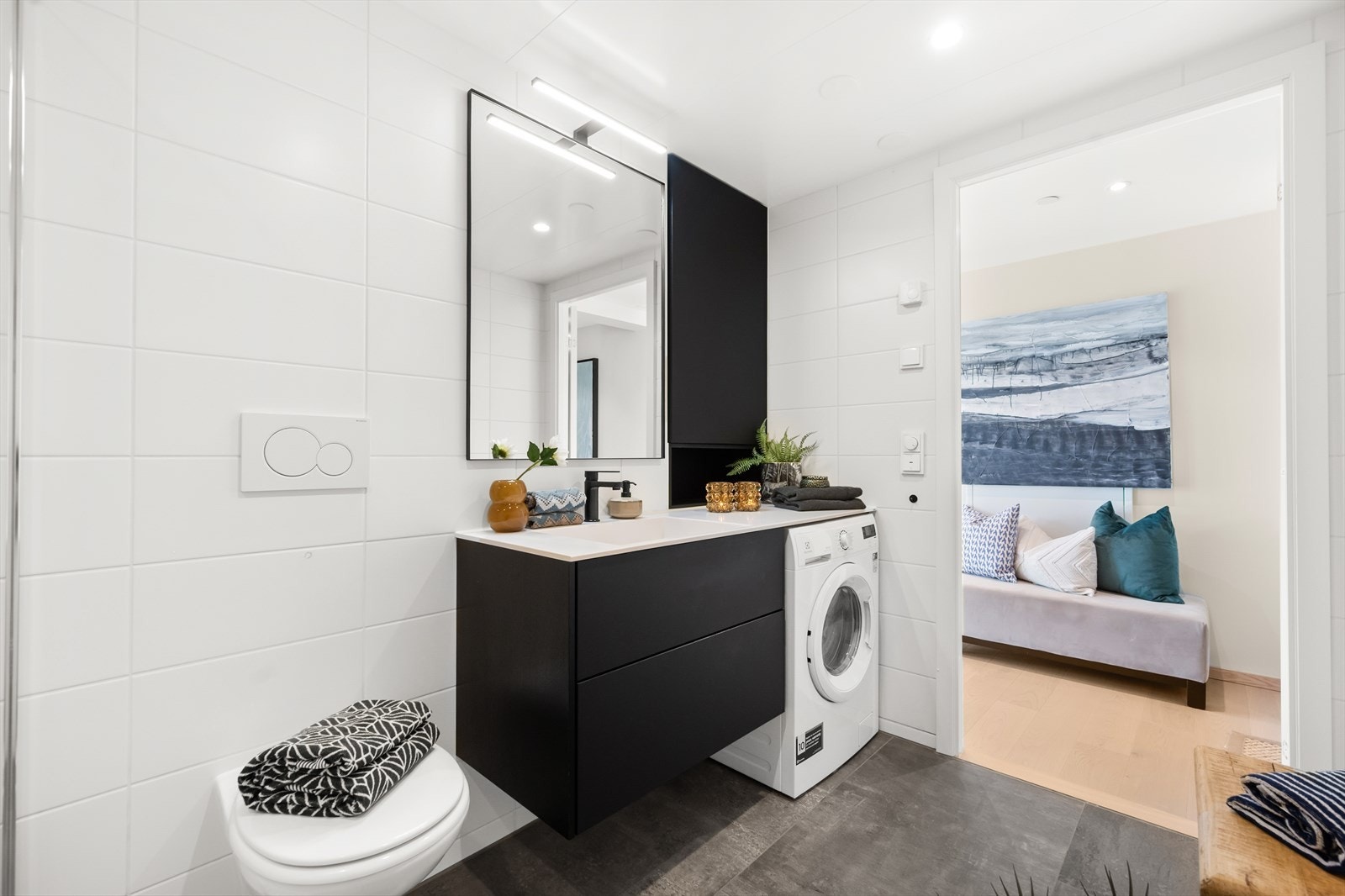 Badet er innredet med vegghengt toalett, dusjnisje med glassvegg og baderomsinnredning med heldekkende servant, speil og skuffer. Galleribilde