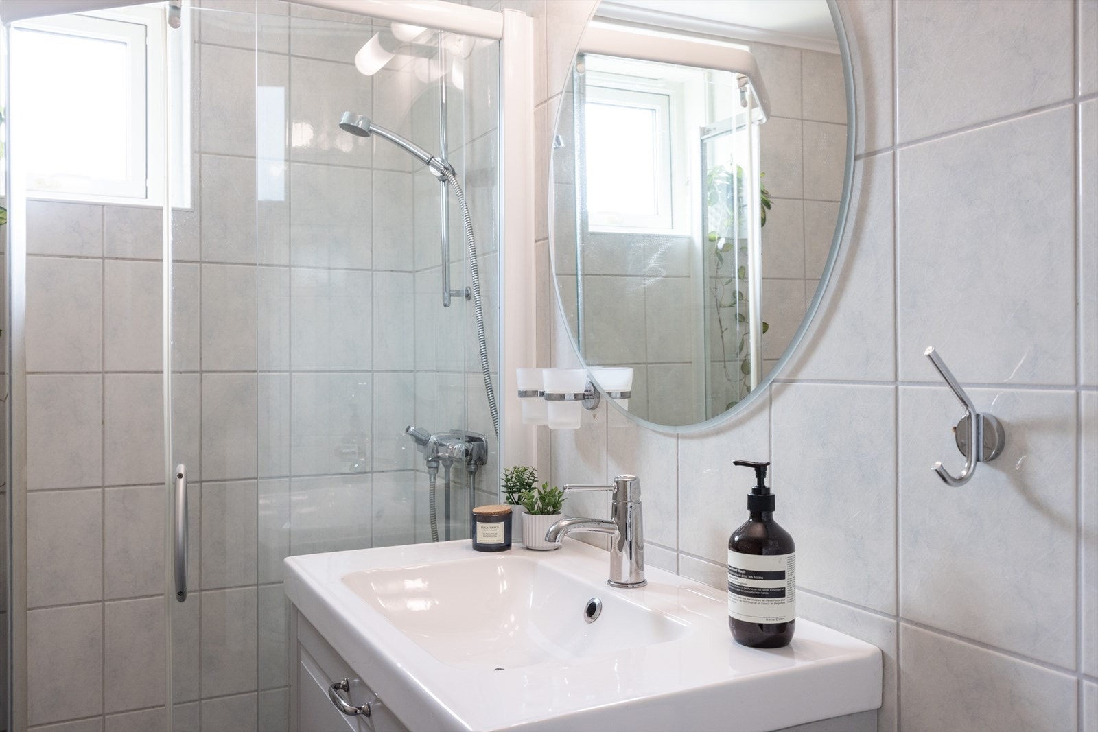 Badet er innredet med servantskap med profilerte, folierte fronter og heldekkende servant, speil og lysarmatur på vegg over servant, gulvmontert klosett og dusjhjørne med skyvedør. Galleribilde