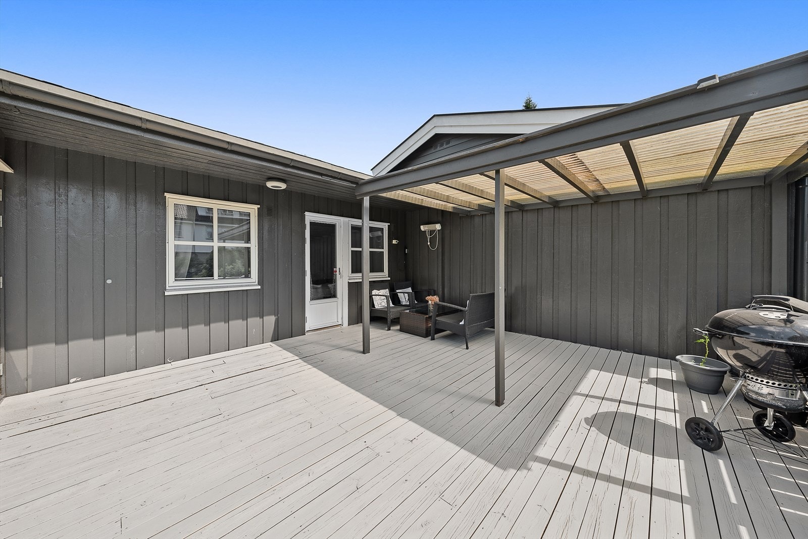 Sydvendt terrasse på ca. 29m² med beiset tregulv og delvis takoverbygg - et flott uterom. Galleribilde