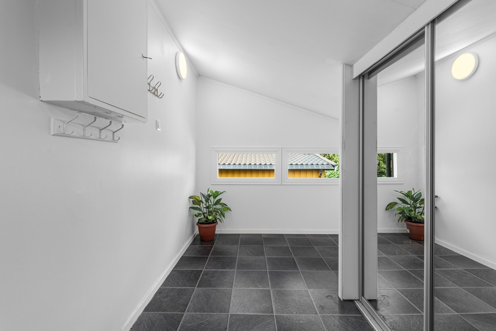 Romslig inngangsparti med flislagt gulv og vinduer gir et luftig førsteinntrykk. Galleribilde