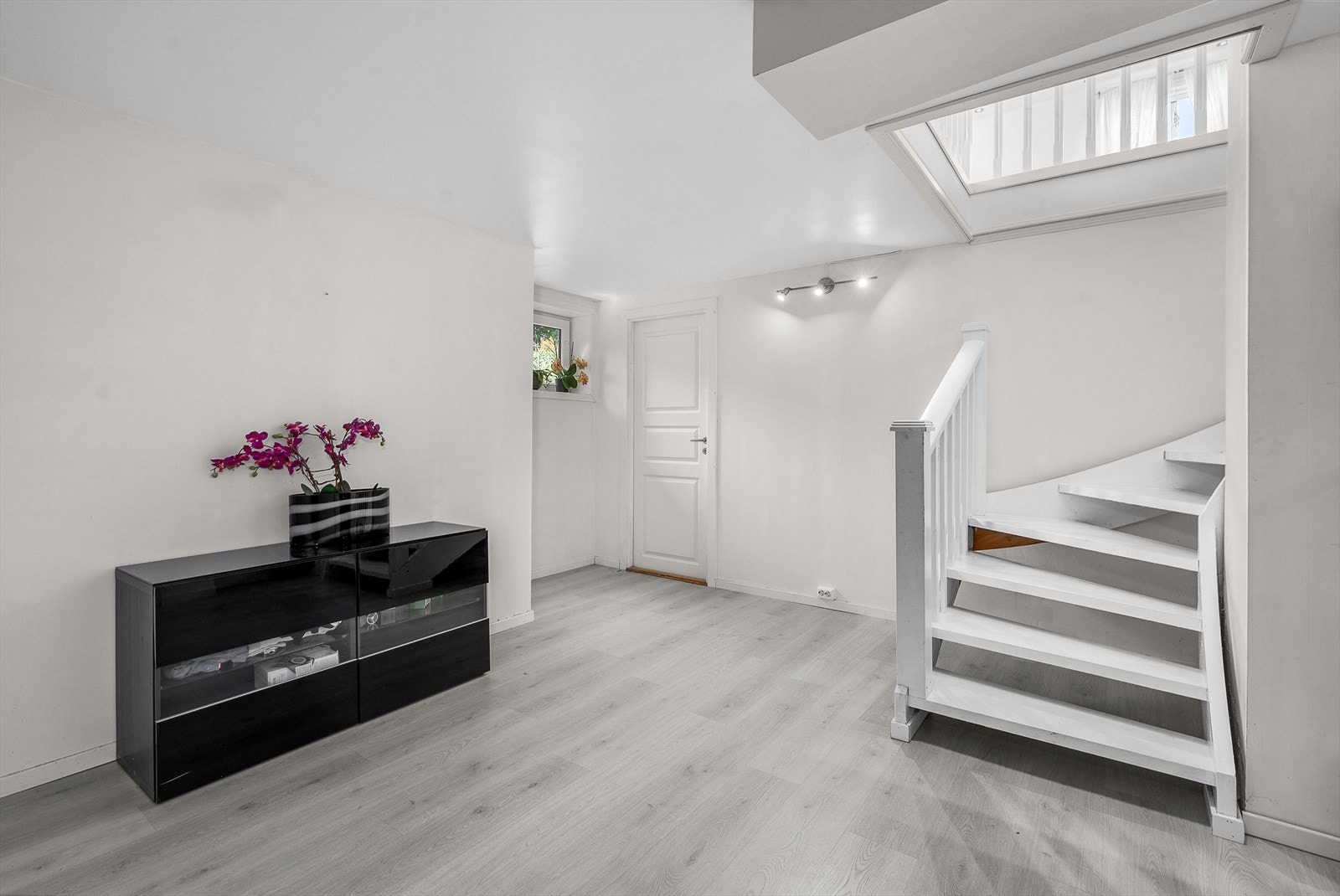 Kjellerstue med moderne laminatgulv og direkte adkomst fra hovedetasjen via malt tretrapp. Galleribilde