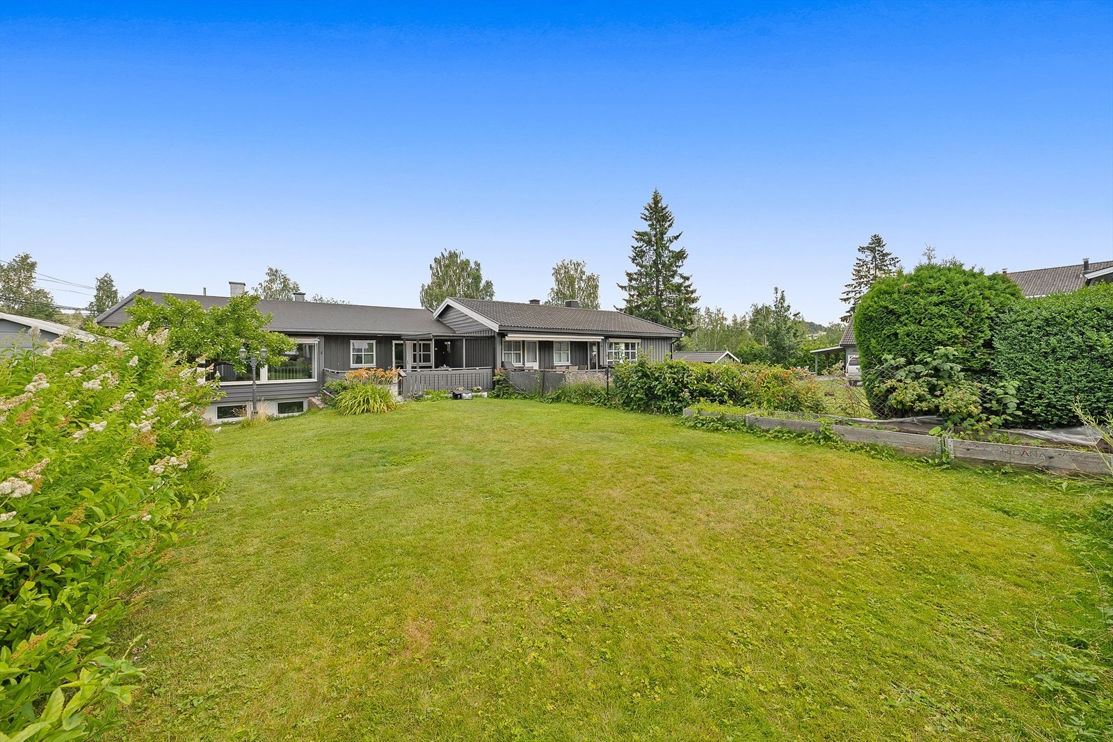 Romslig tomt med plen og beplantning, ideell for barnefamilier og hageentusiaster. Galleribilde