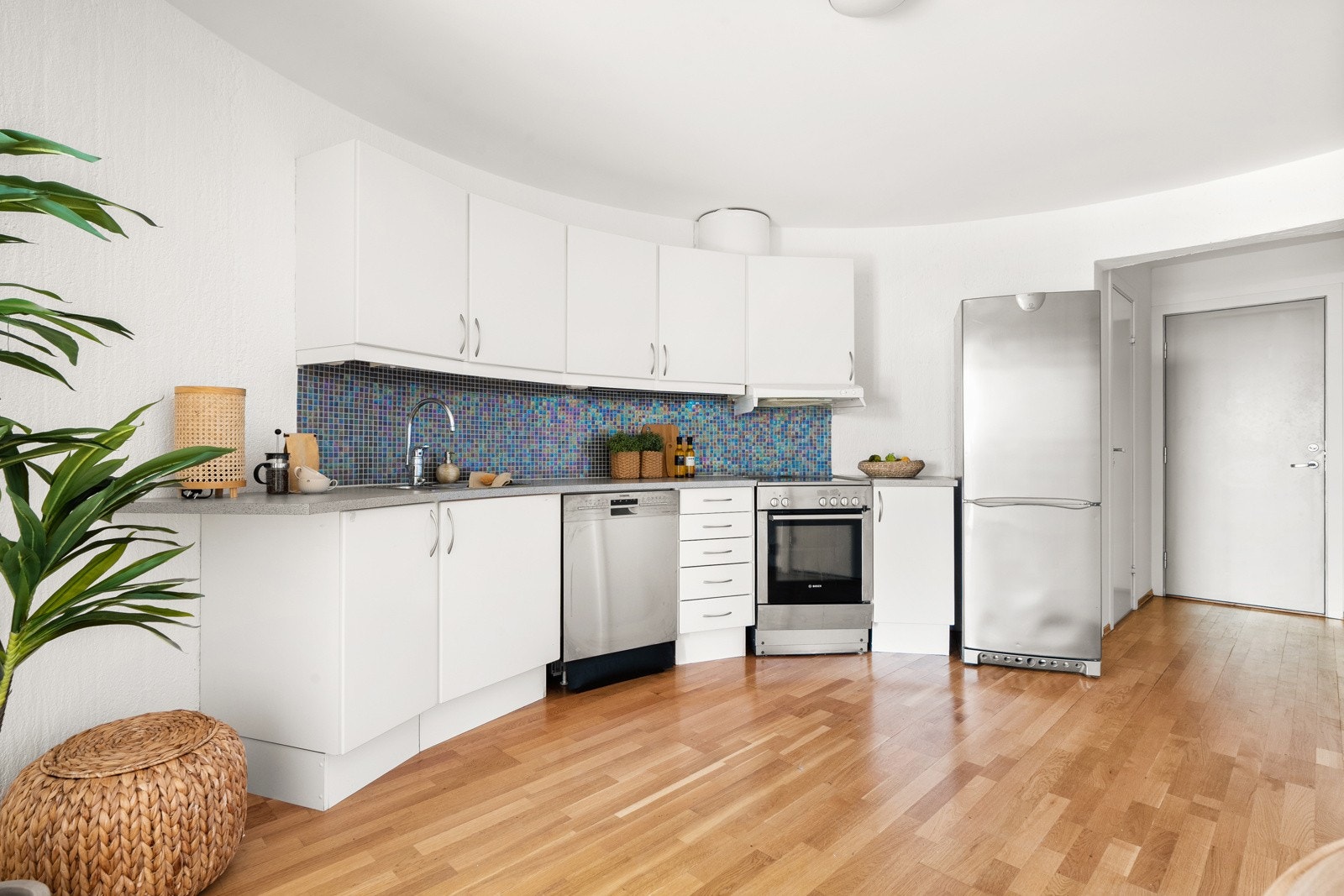 Kjøkkenet har en tidløs innredning med lyse, glatte fronter, laminat benkeplate og dekorative fliser mellom kjøkkenbenk og overskap. Galleribilde