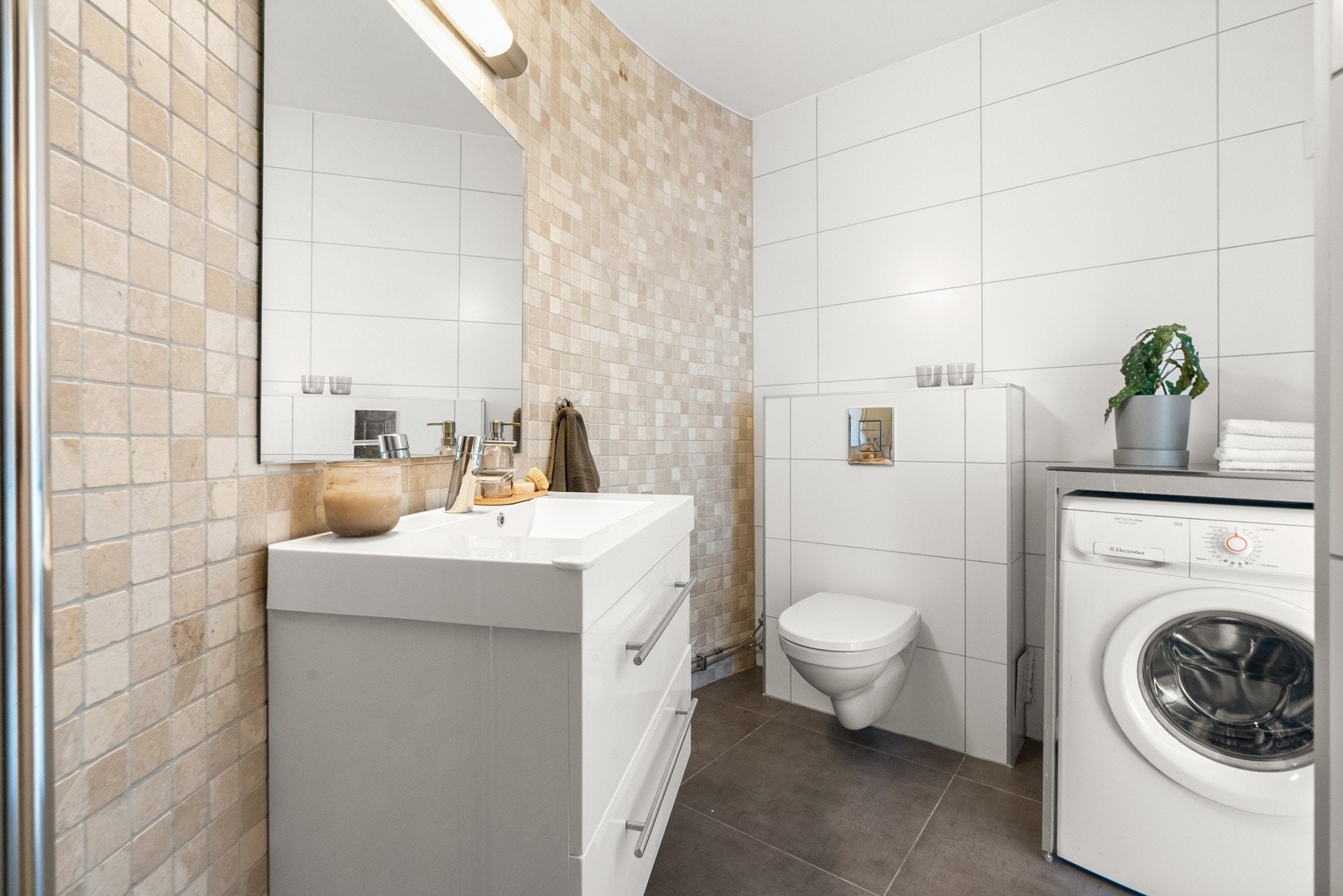 Baderommet har vegghengt servantinnredning med skuffer, ovenpåliggende servant med ett-greps armatur, speil med overlys og stikkontakt over servant. Galleribilde