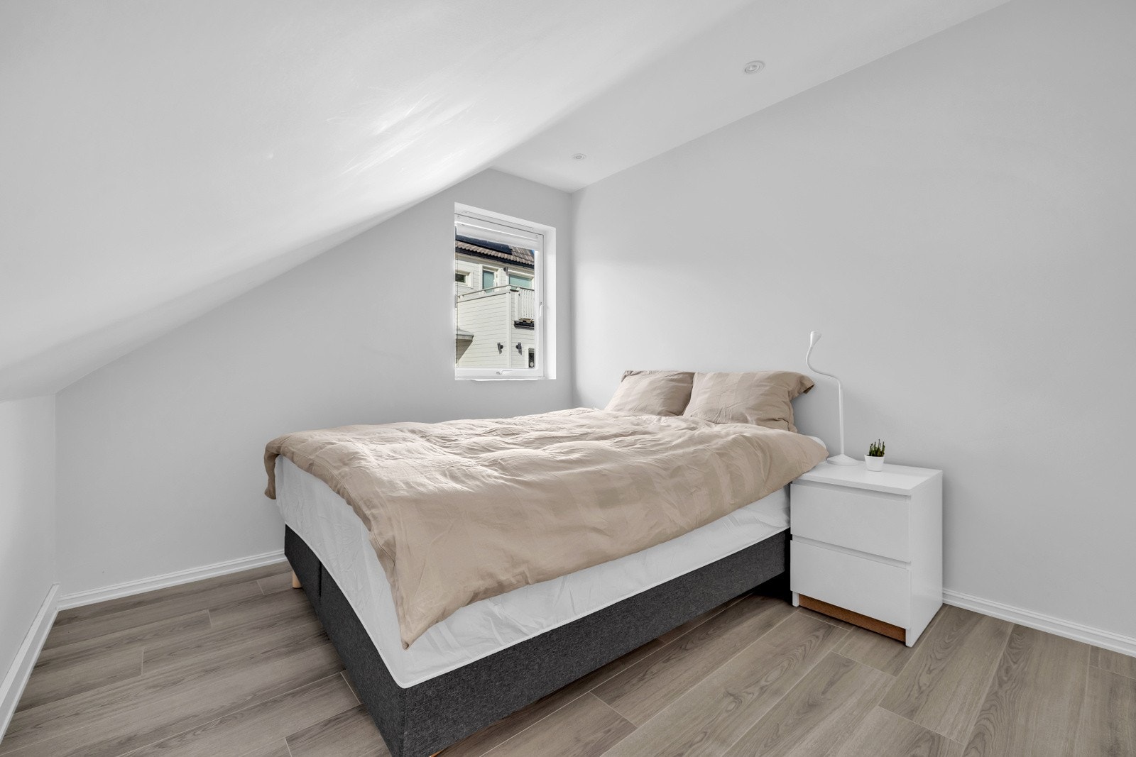 Soverom 2 er hvitmalt med samme gjennomgående laminat på gulvene. Rommet er innredet med en dobbeltseng og nattbord og har god plass til garderobe eller kommode for oppbevaring. Galleribilde