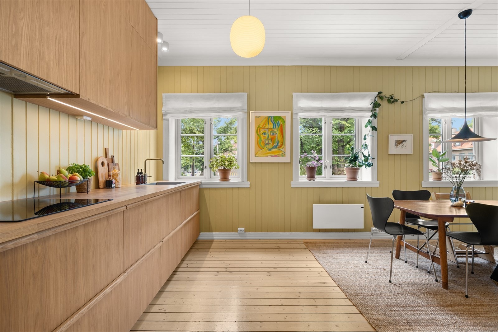 Lyst og moderne kjøkken i åpen løsning mot stue og spiseplass, med god benkeplass og integrerte hvitevarer. Galleribilde