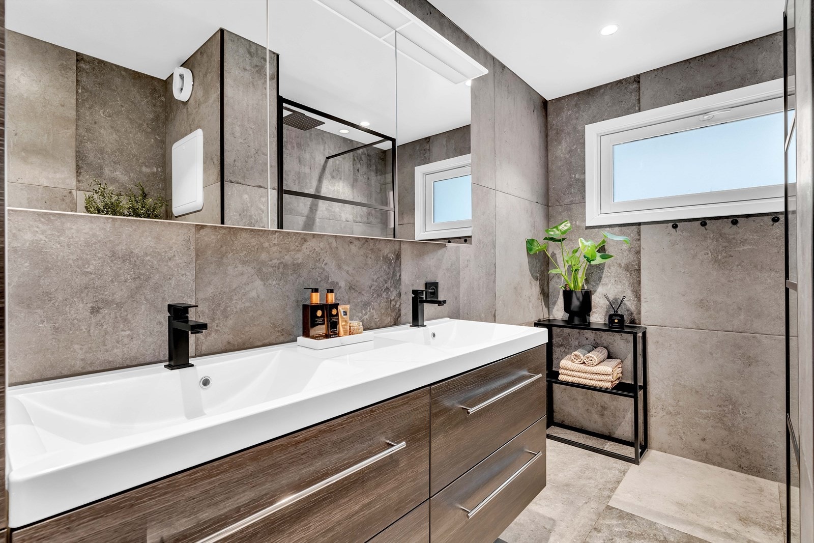 Badet fremstår som meget delikat og inneholder heldekkende servant, speilskap på vegg, dusjhjørne med glassvegg, og veggmontert toalett. Galleribilde