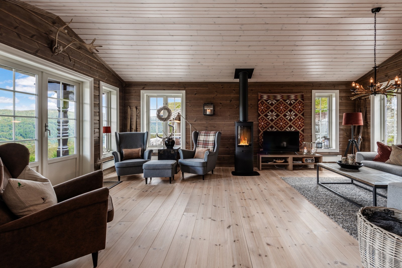 Lun og innbydende stue med peis - perfekt for koselige kvelder med familie og venner. Store vinduer slipper inn naturlig lys og gir en fantastisk utsikt til naturen utenfor. Galleribilde