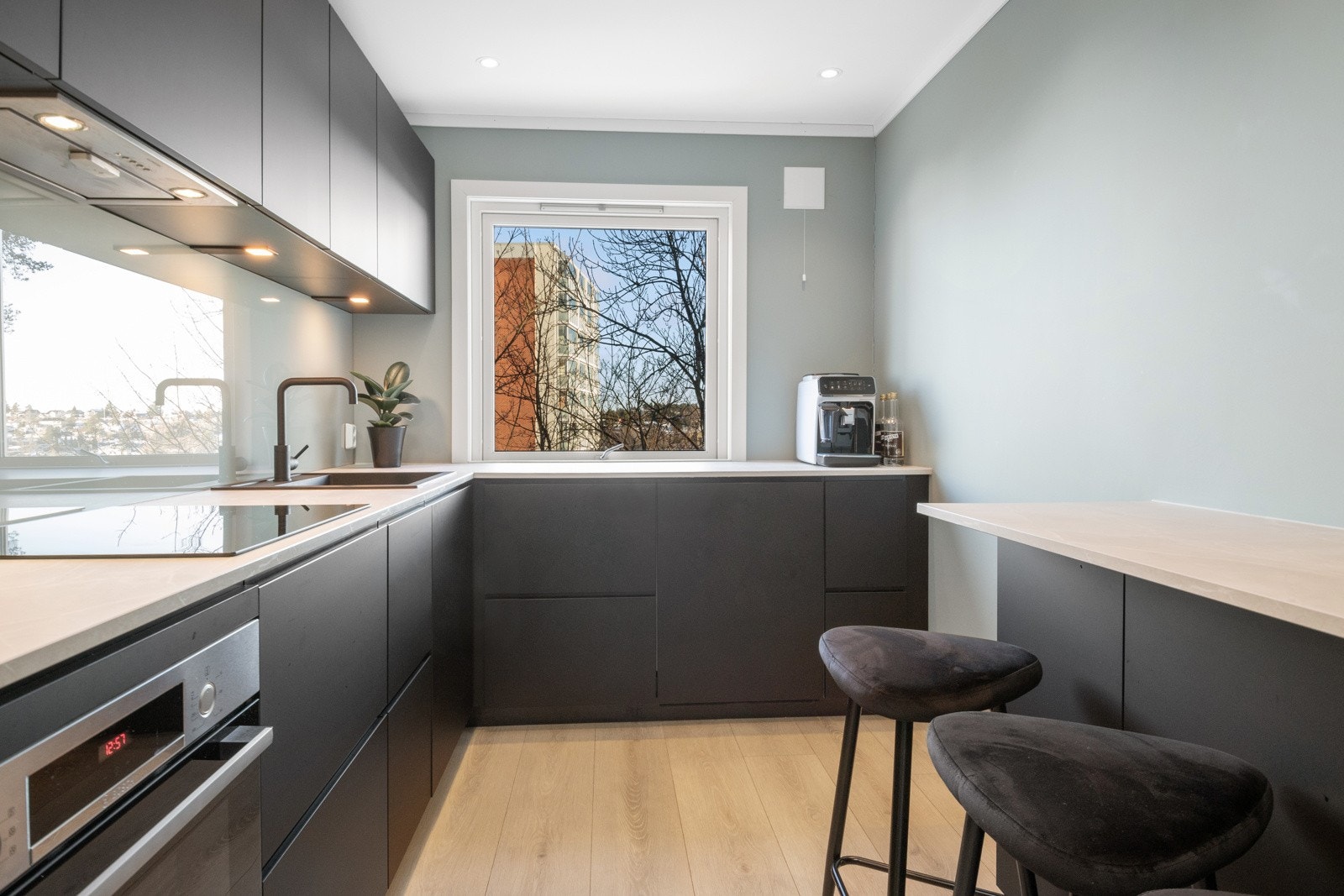 Innenfor entreen har leiligheten et stilrent og moderne kjøkken Galleribilde