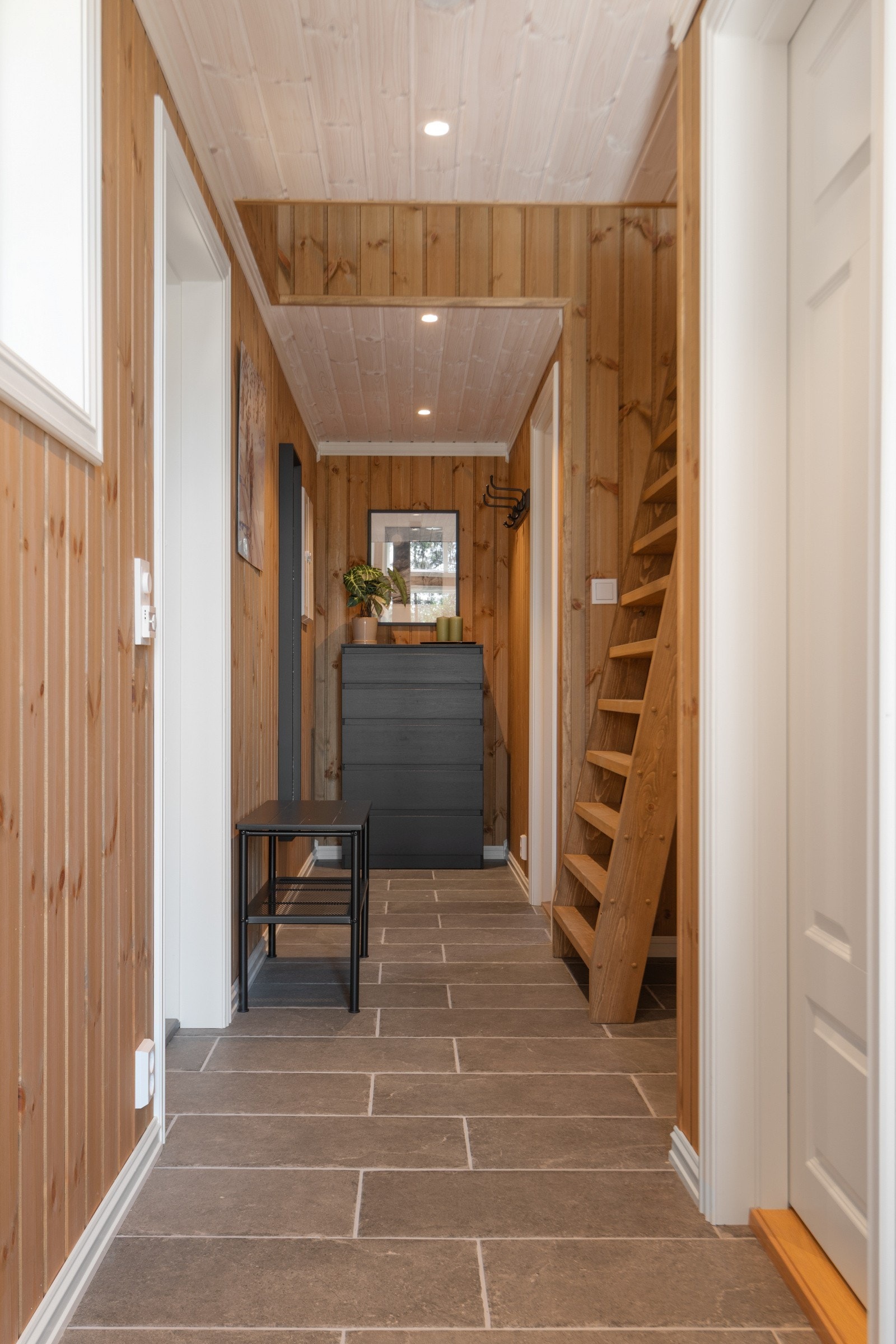 Gang med fliser og varmekabler, plass til garderobeløsning innerst i gangen, trapp/stige opp til hemsen. Galleribilde