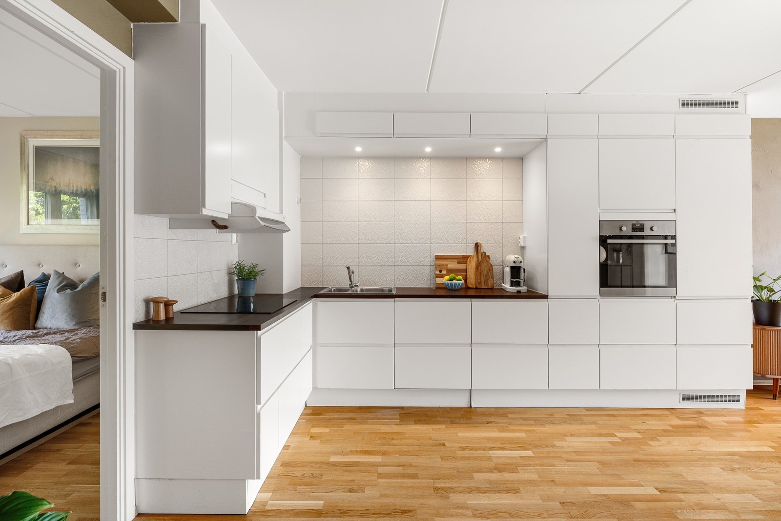 Lys, glatt kjøkkeninnredning med laminert benkeplate og nedfelt oppvaskkum med ett-greps armatur. Galleribilde