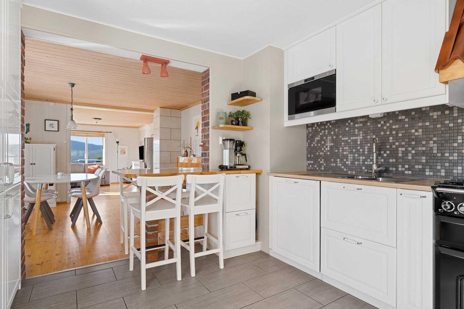 Kjøkken med folierte skrog og slette fronter, utstyrt med bl.a. kombiskap, oppvaskmaskin, ventilator, stekeovn og gassfyrt platetopp Galleribilde