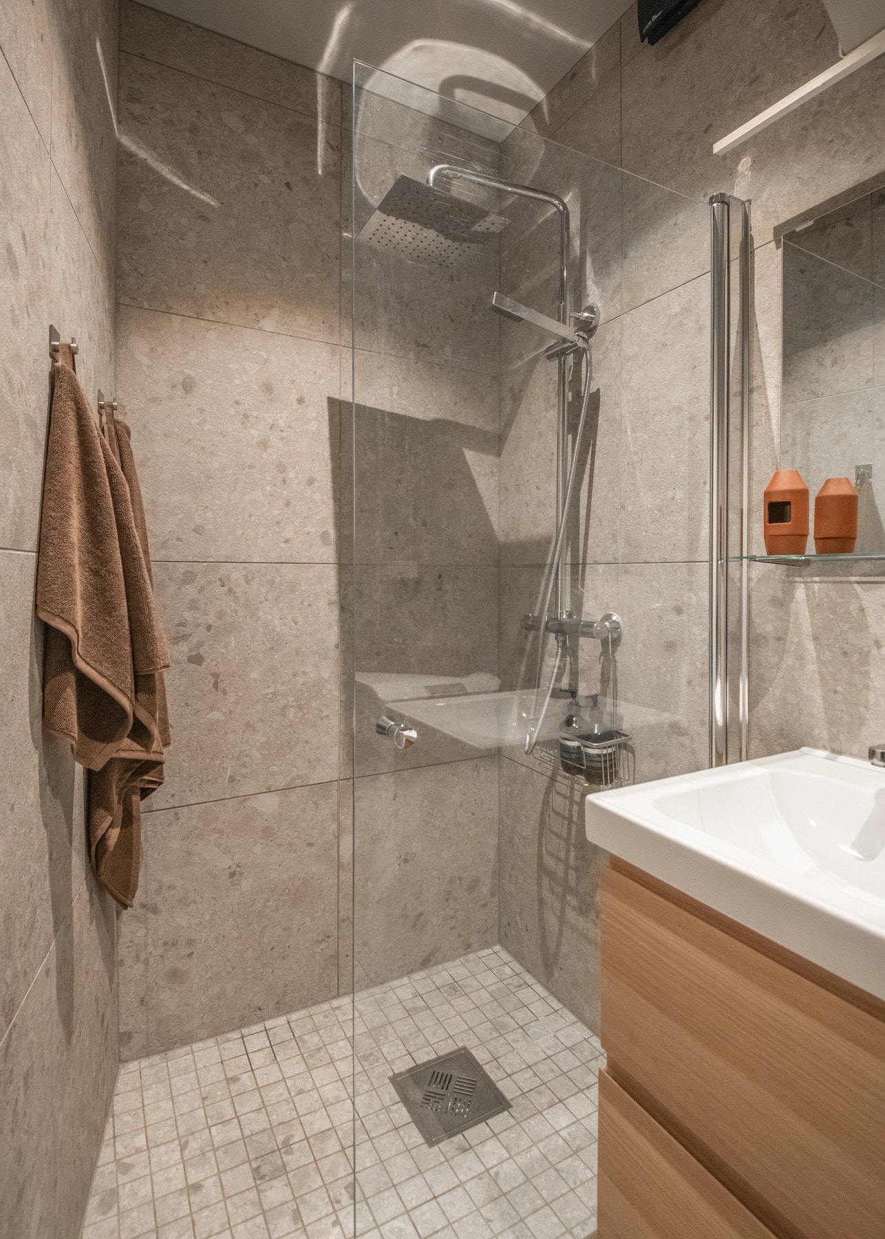 Rommet er helfliset med smakfull materiale på både gulv og vegger, og det er lagt varmekabler i gulvet for lun komfort. Galleribilde