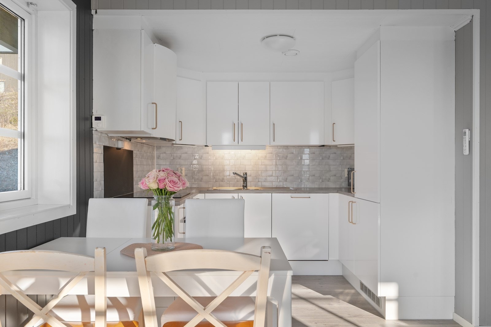 Lekkert kjøkken med folierte skrog med slette fronter og laminert benkeplate. Vinylflis på vegg over benkeplate. Galleribilde