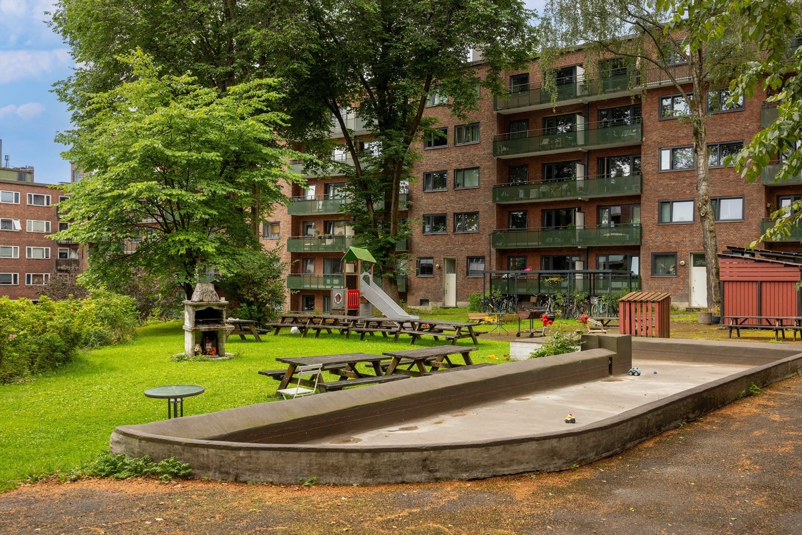 Stor og pent opparbeidet bakgård med flere sittegrupper og lekeapparater m.m. Galleribilde