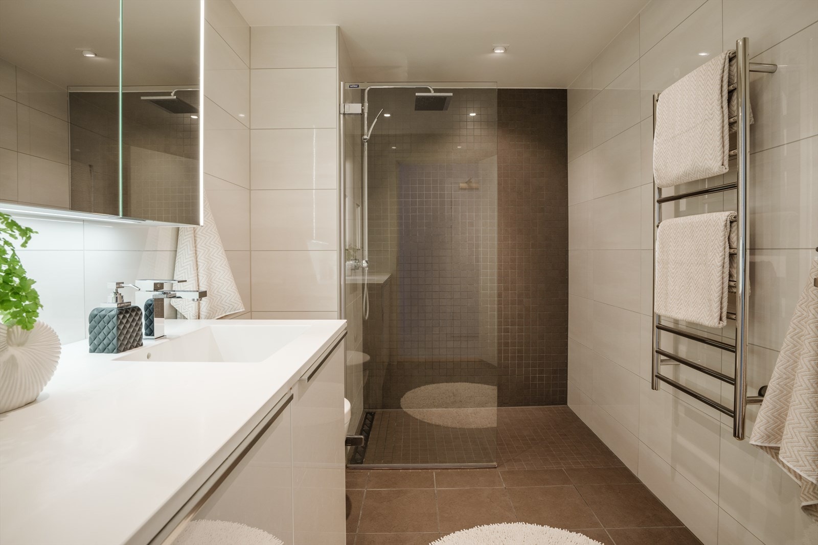 Leilighetens bad ble rehabilitert i 2015. Baderommet har hvite fliser på veggene samt gråbrune fliser på én vegg. Videre er det gråbrune fliser over varmekabler på gulvet og downlights i tak. Galleribilde