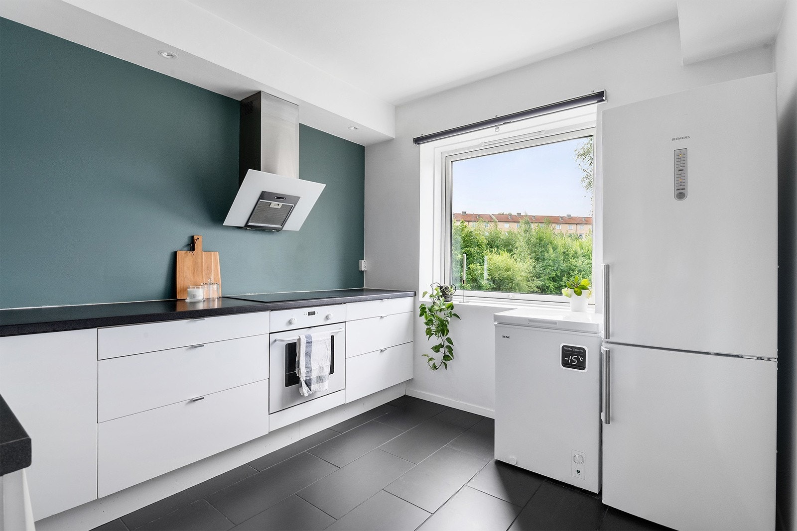 Her kommer du inn i et hyggelig og separat kjøkken som er malt med kontrast vegg i en lun grønntone. Kjøkken innredningen består av glatte hvite fronter. Galleribilde