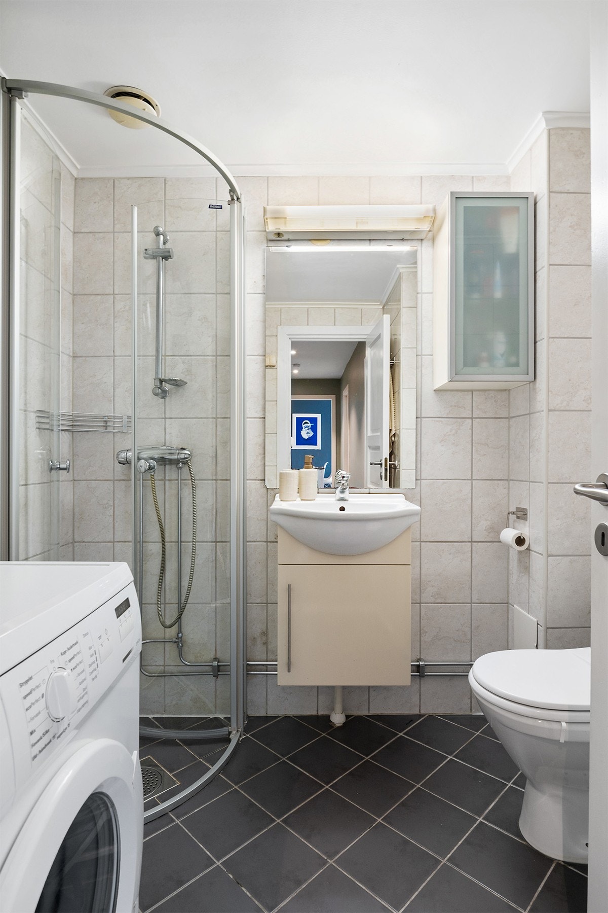 Flislagt bad med varme i gulv. Det er servant med underskap speil med overlys. Galleribilde