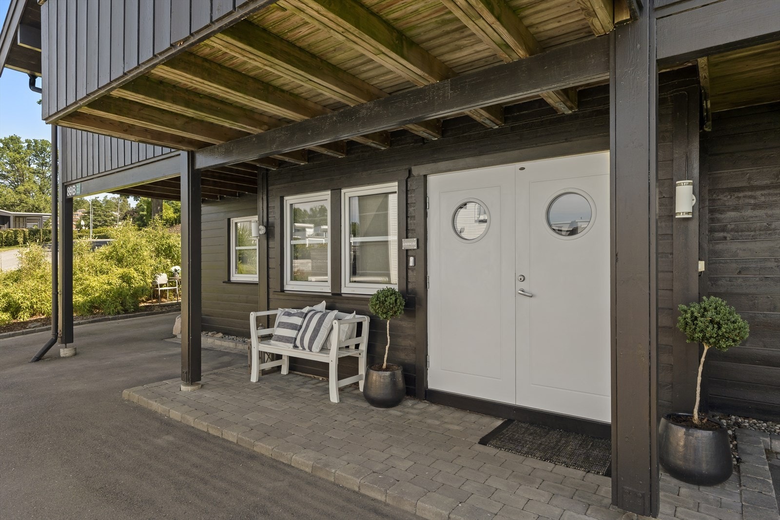 Inngangsparti med takoverbygg og steinbelagt område. Galleribilde