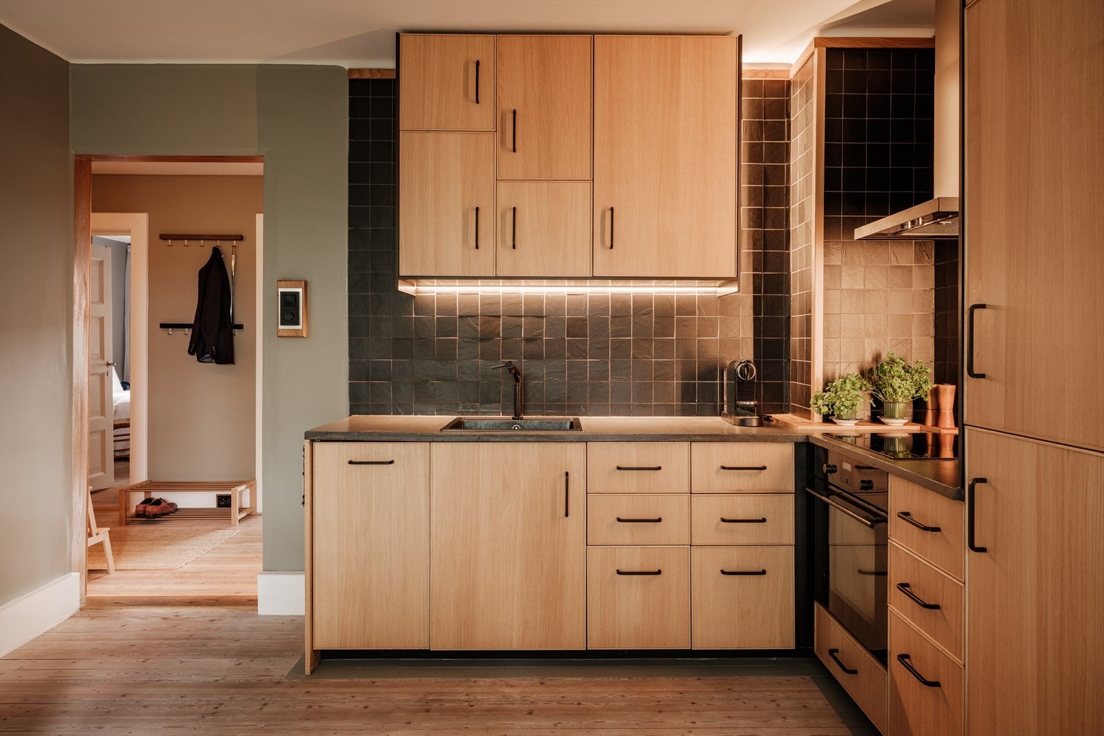 Kjøkkeninnredning fra IKEA med slette fronter, støpt benkeplate, flis mellom overskap og benk. Nedfelt oppvaskkum og ventilator med kullfilter over kokeplass. Galleribilde