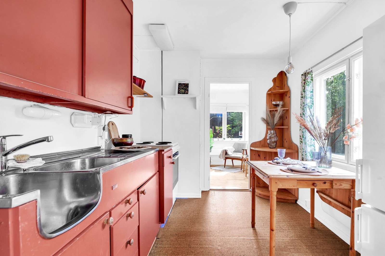 Kjøkkenet består av moduler med rødmalte slette fronter, kjøleskap, nedfelt vask, benkeplate og frittstående stekeovn. Galleribilde