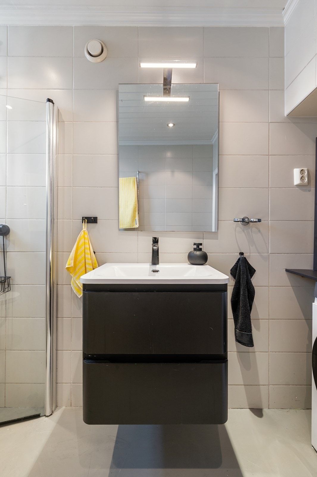 Her får du et praktisk dusjhjørne med innfellbare glassvegger, vegghengt toalett og et stilrent servantskap med god oppbevaringsplass. Galleribilde