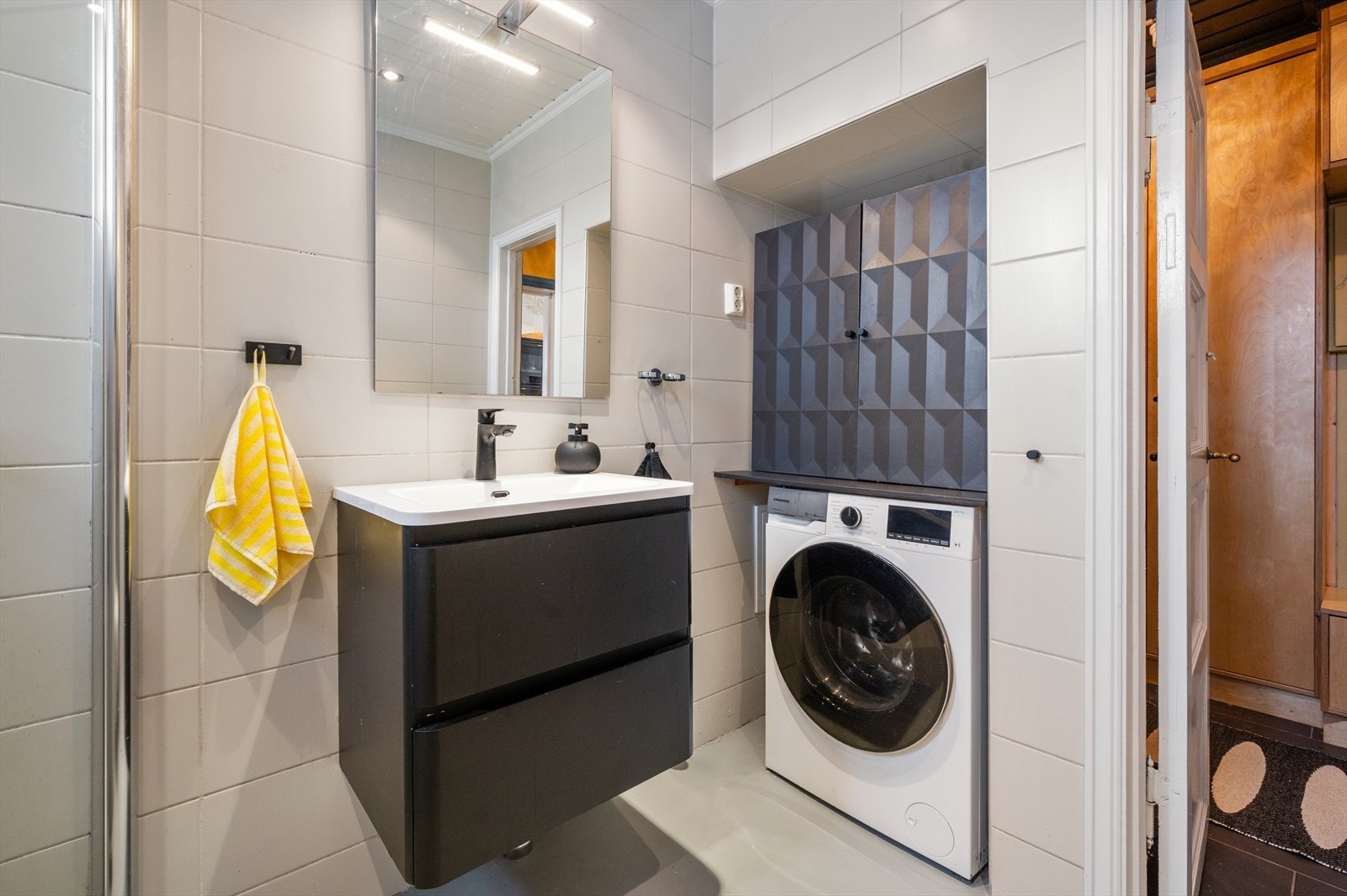 Over servanten finner du et stort speil med integrert belysning som gir både funksjonalitet og en følelse av romslighet. Videre er badet utstyrt med opplegg for vaskemaskin. Flislagt gulv med gulvvarme og flislagte vegger. Galleribilde