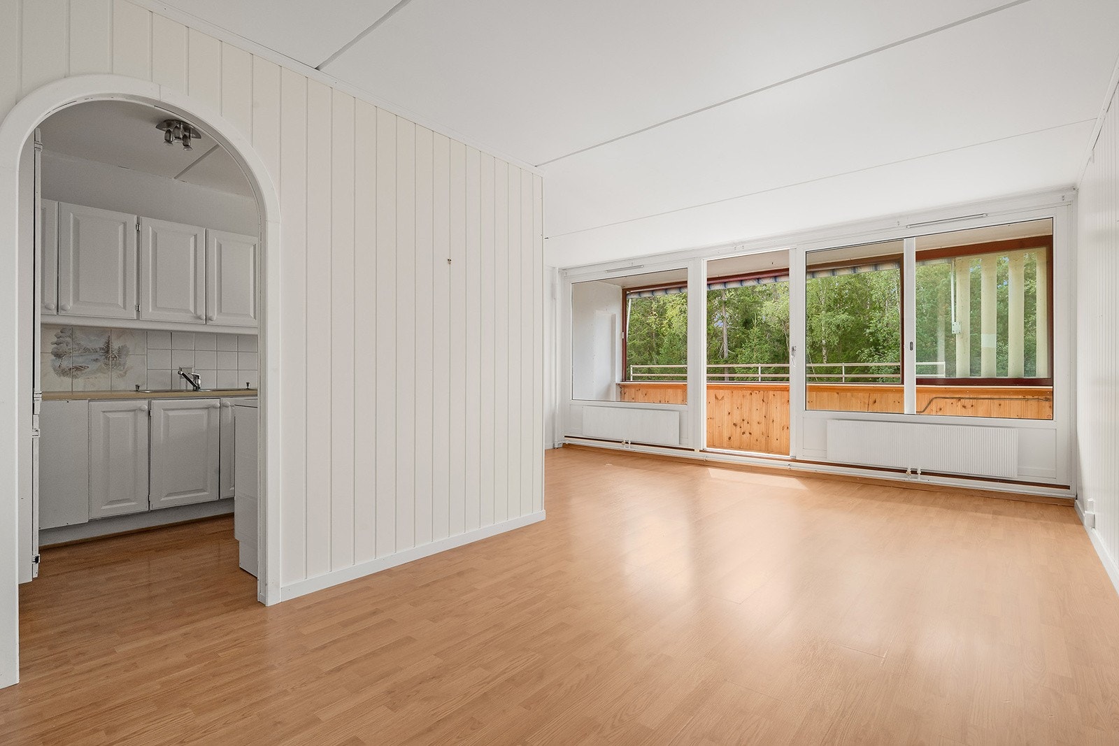 Lys og romslig stue med store gode vindusflater. Stuen har hvite MDF plater på veggene og laminatgulv. Det er adkomst fra stuen til kjøkkenet. Galleribilde