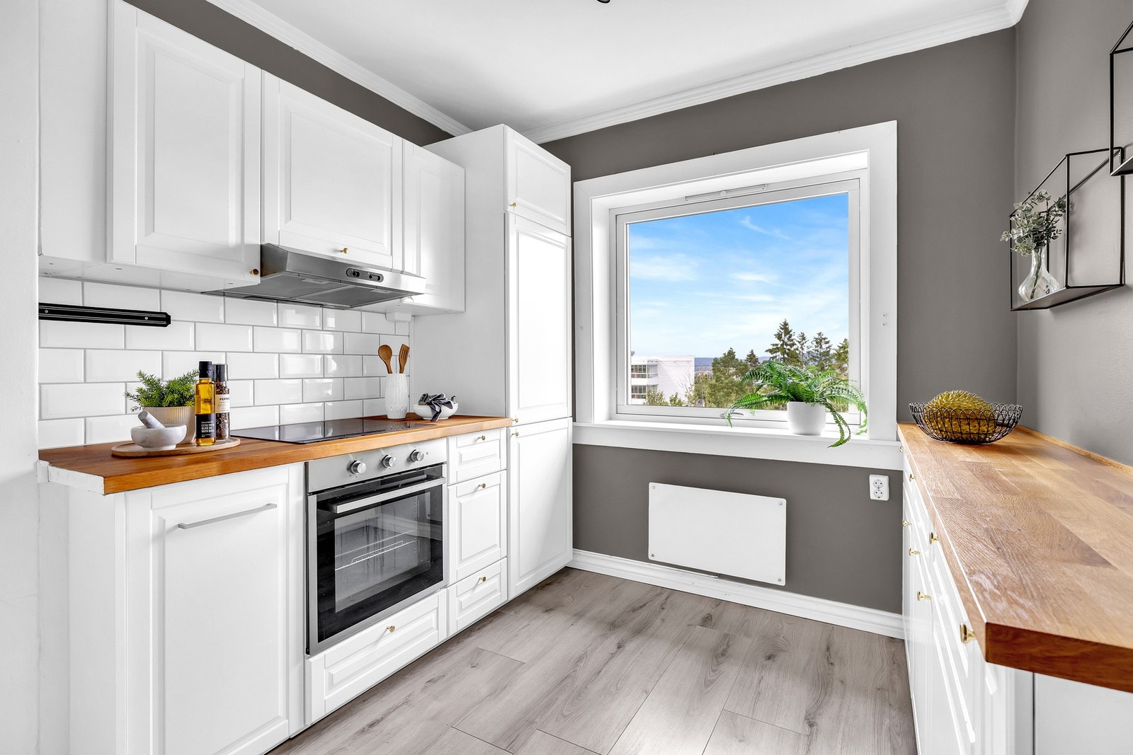 Innredningen har hvite profilerte fronter og benkeplate i tre, med fliser mellom benk og overskap som gir et rent og klassisk uttrykk. Galleribilde