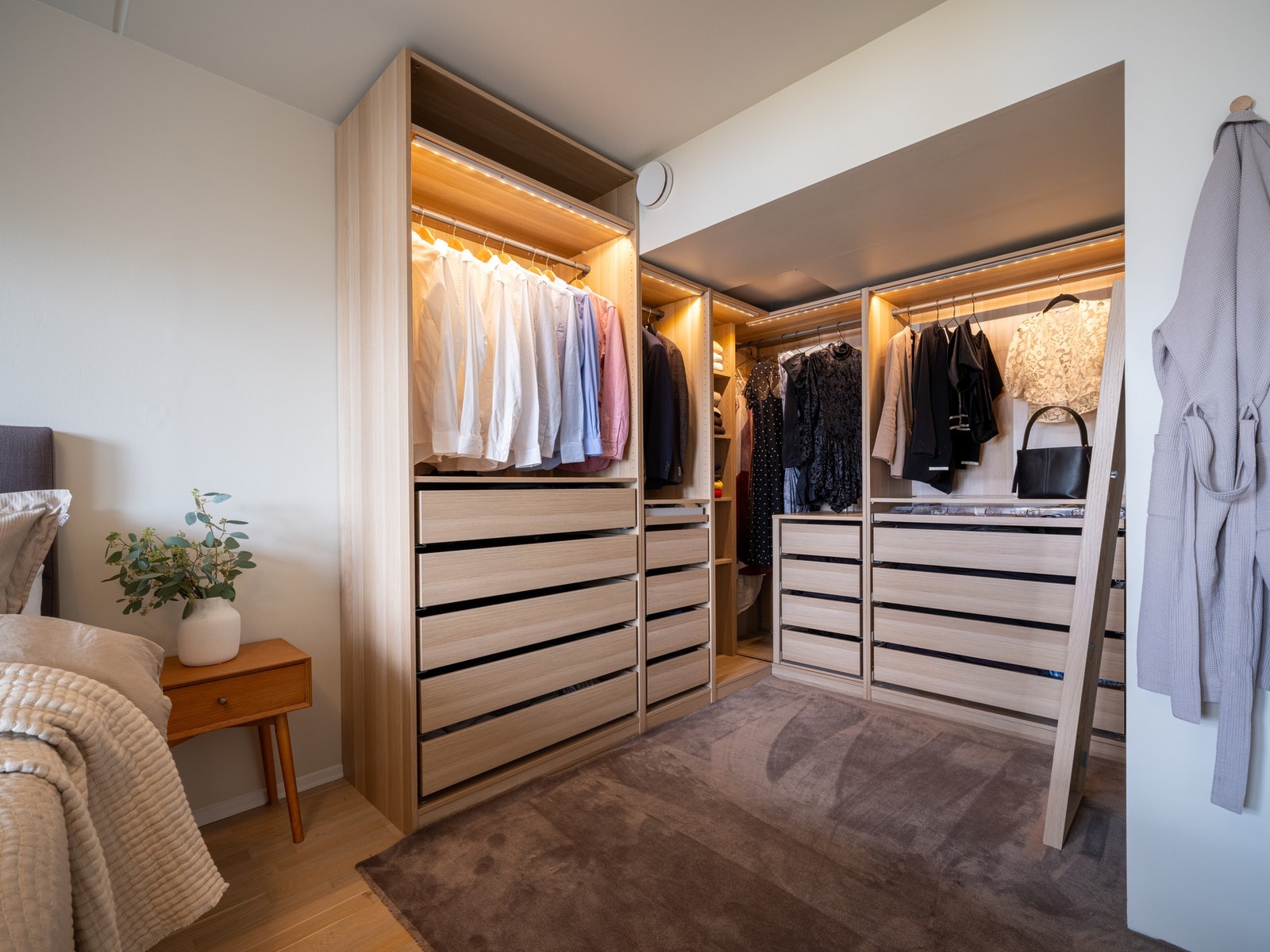 Pen garderobe med praktiske løsninger og integrert belysning som gjør at du enkelt kan finne klærne dine på morningen uten å lyse opp hele rommet. Galleribilde