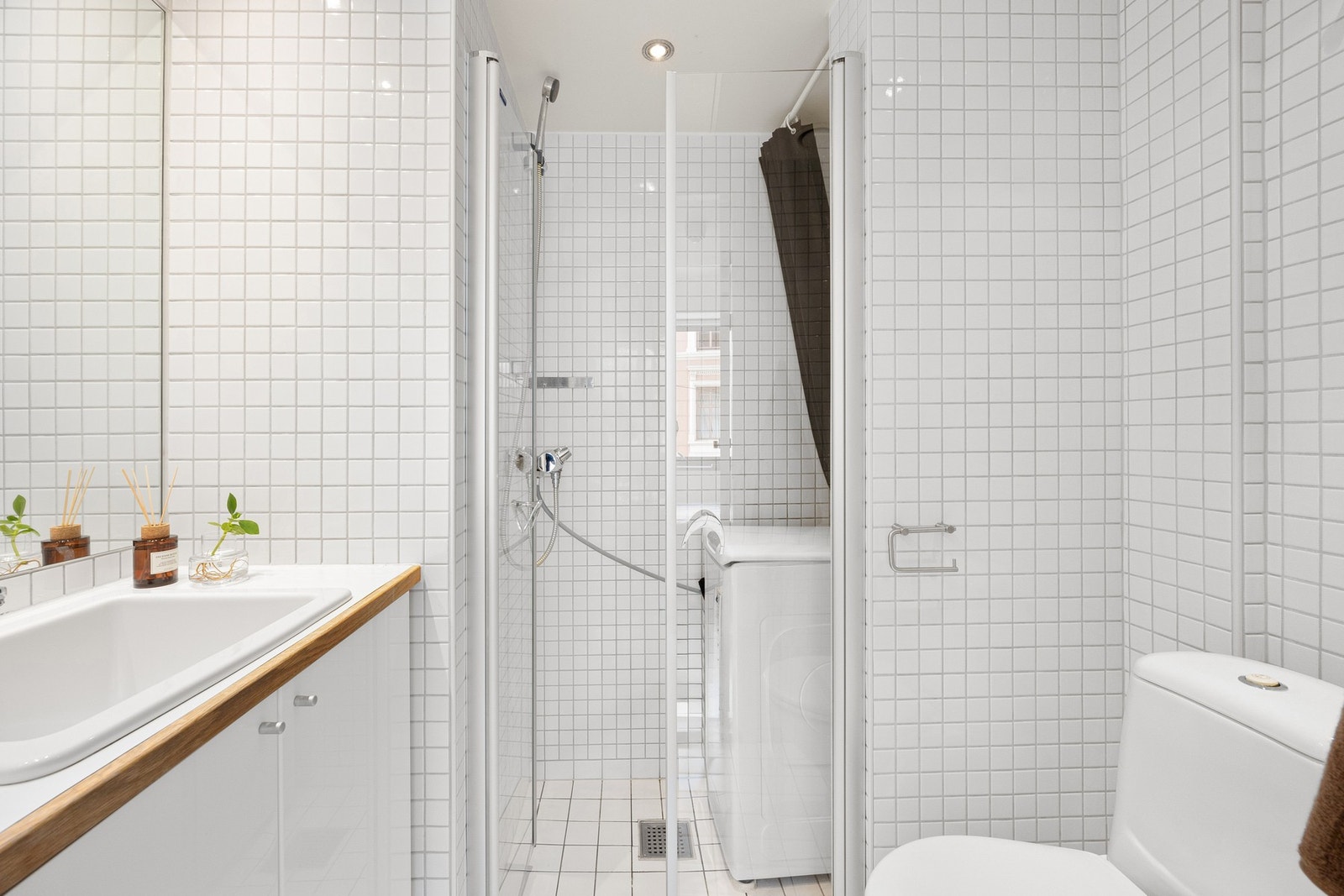 Hybelbadet er pent flislagt med hvite fliser og dusjnisjeog servant Galleribilde