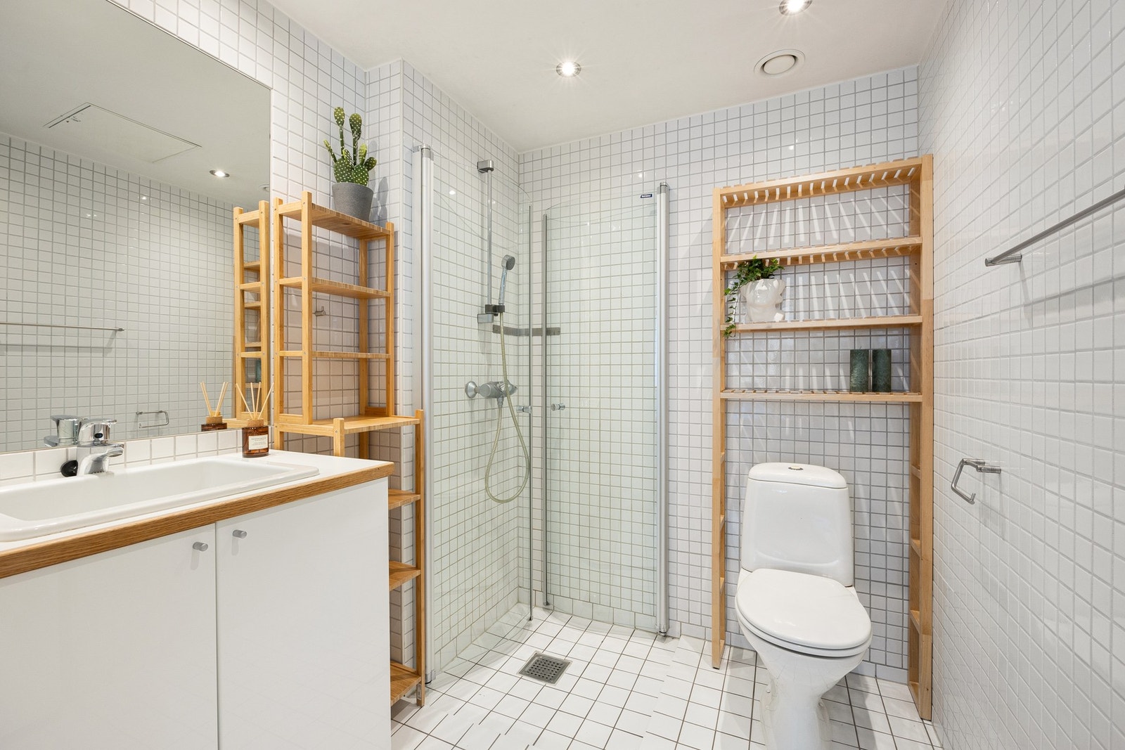 Leiligheten har 2 komplette bad. Dette er hovedbadet som pent flislagt med hvite fliser og med stor og praktisk servant Galleribilde