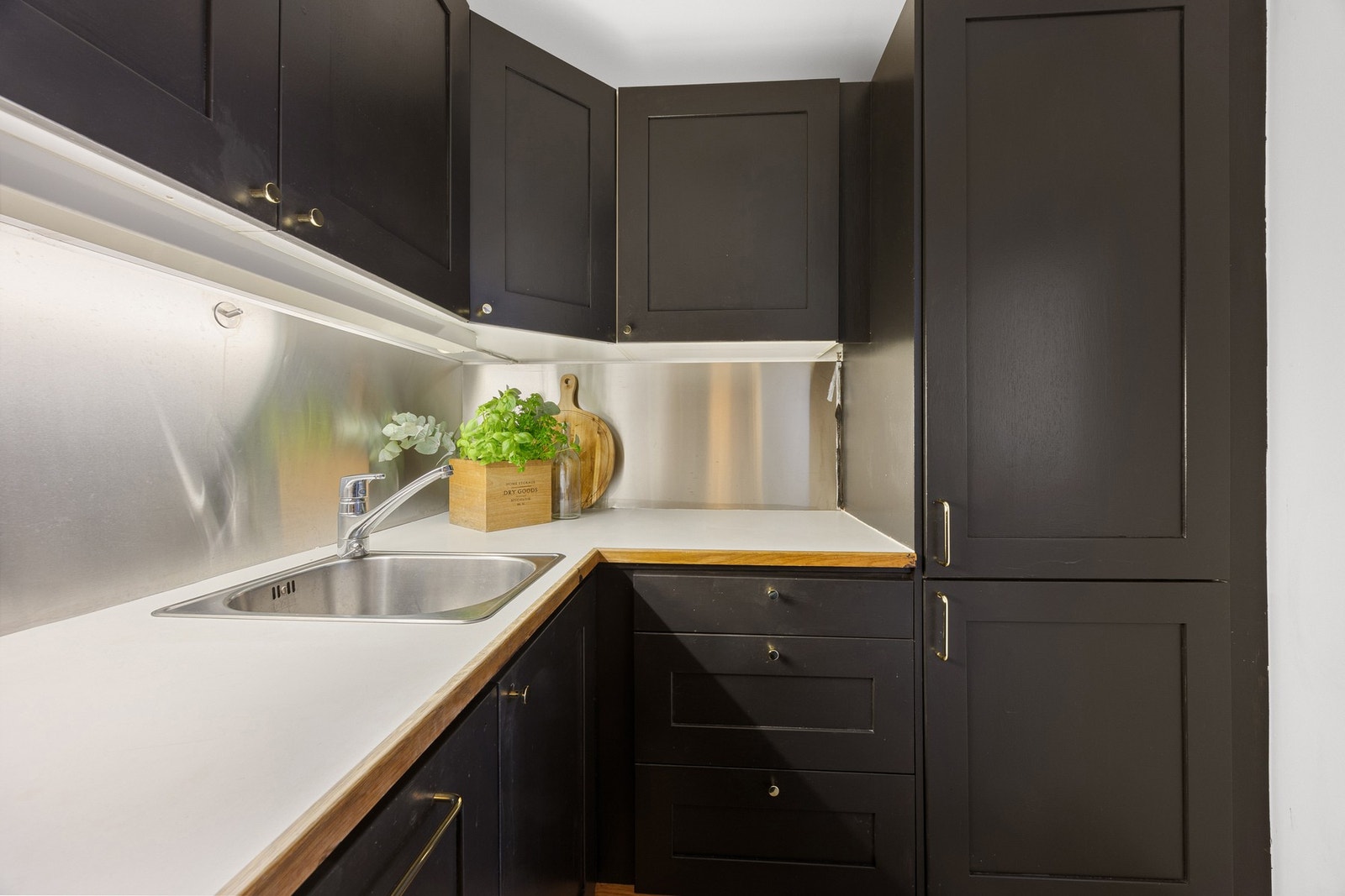 Kjøkkenet har sorte fronter og integrerte hvitevarer som følger med uten garanti Galleribilde