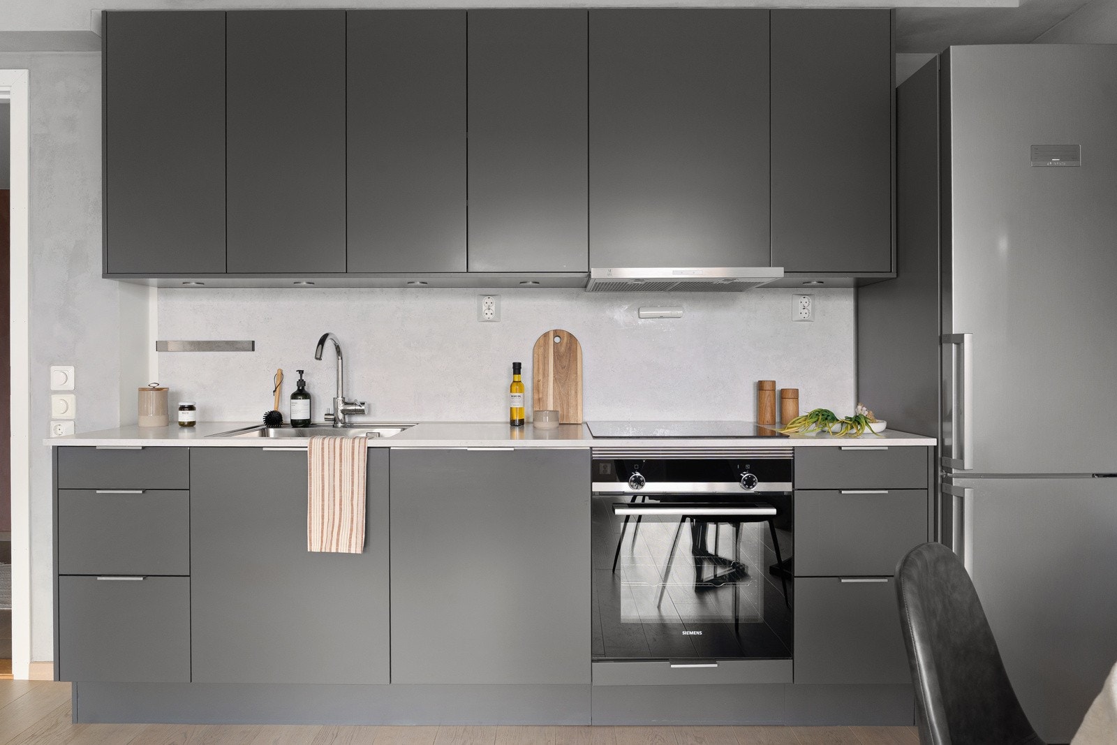 Lys laminat benkeplate med nedfelt stålkum og ett-greps armatur i krom. Kjøkkenet er utstyrt med integrerte hvitevarer fra Siemens, som oppvaskmaskin, stekeovn og platetopp, samt avtrekksvifte fra Røroshetta. Det er også opplegg for kjøl/frys. Galleribilde