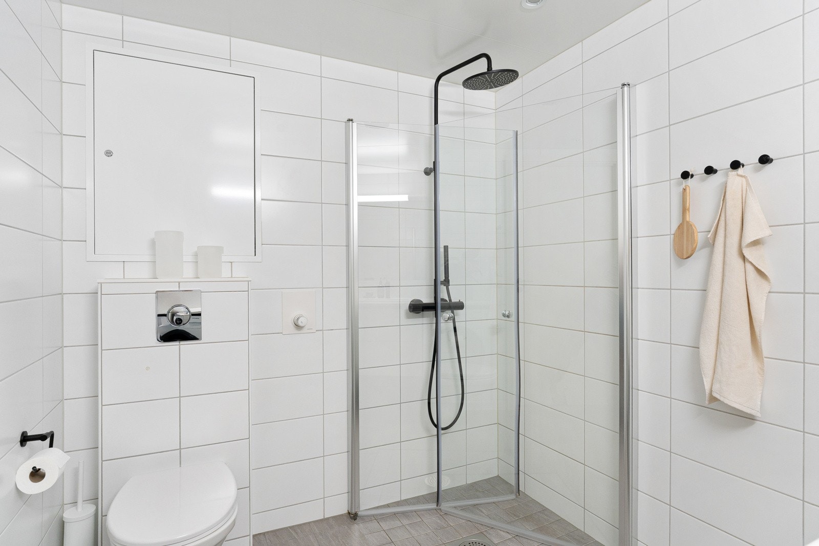 Stilrent bad fra byggeår med vannbåren gulvvarme og flislagte flater. Praktisk dusjhjørne med svingbare glassvegger og sort termostatstyrt dusjbatteri med både hånd- og regnfallsdusj. Galleribilde