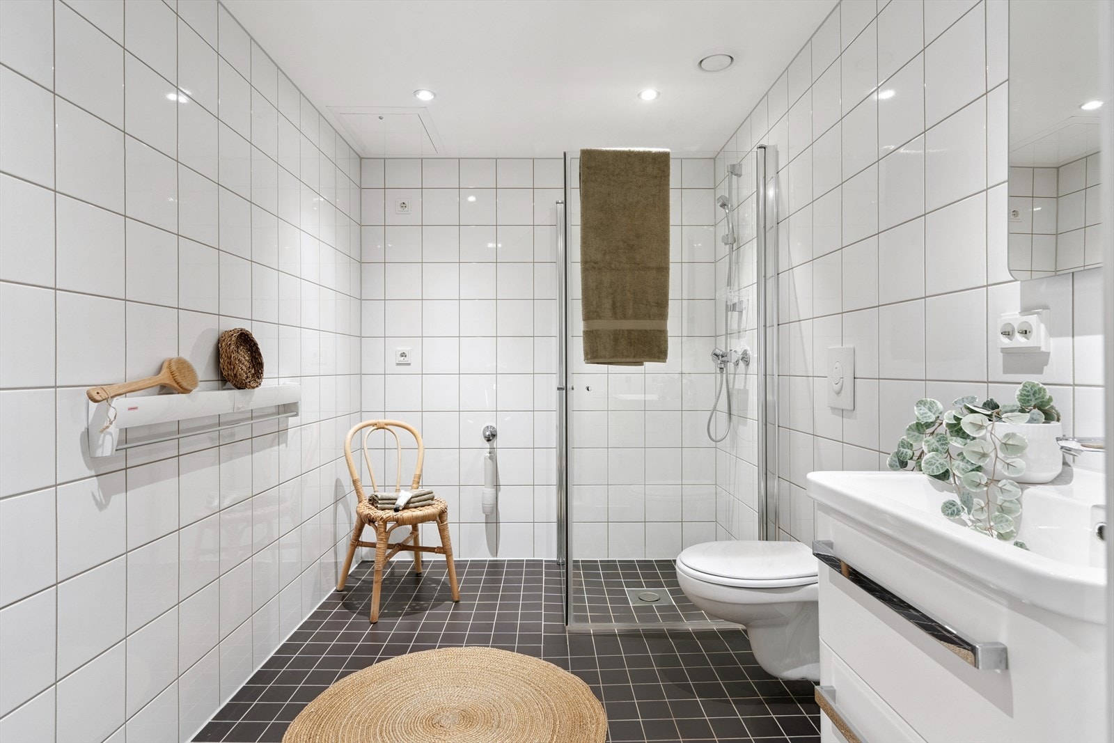 Pent og klassisk bad. Badet er helfliset, og inneholder vegghengt toalett, dusj med vendbare dører og servant med skapinnredning. Badet er av god størrelse, og det er opplegg for vaskemaskin Galleribilde