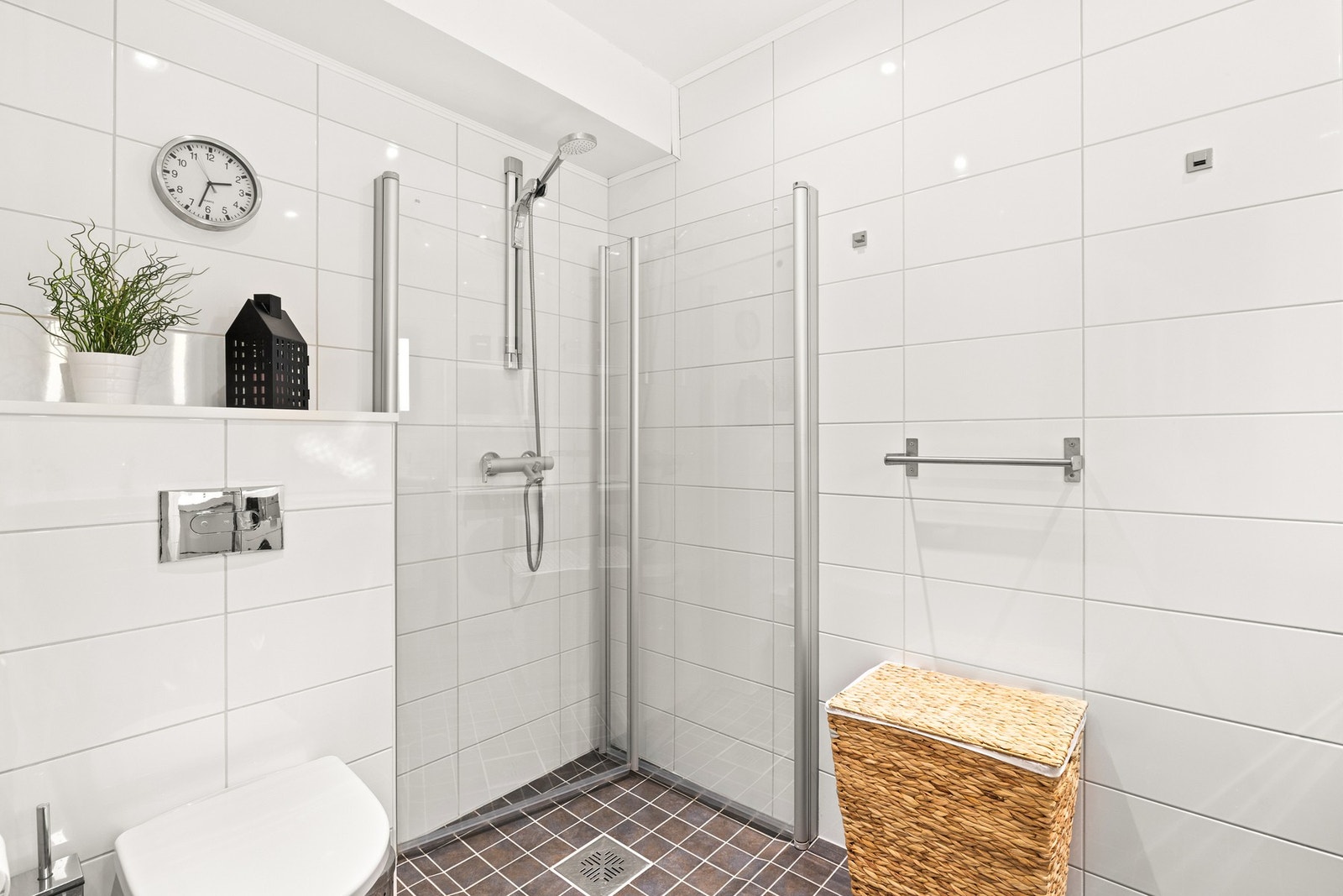 Toalettet er veggmontert for et rent uttrykk, og dusjhjørnet har glassdører, sluk i sone og dusjutstyr. Galleribilde