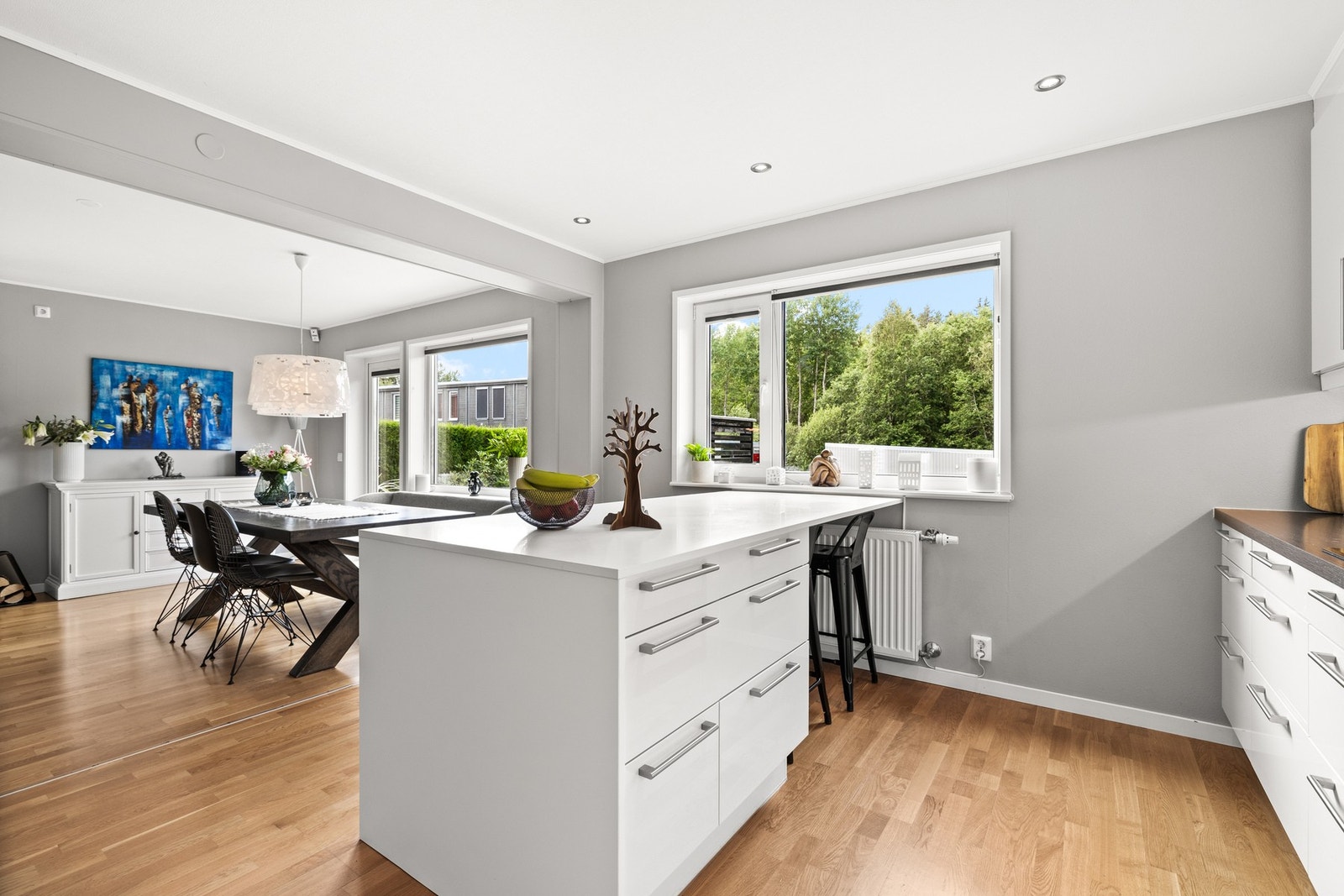 En romslig kjøkkenøy med samme materialvalg gir ekstra benke- og oppbevaringsplass, samt sitteplasser for uformelle måltider. Galleribilde