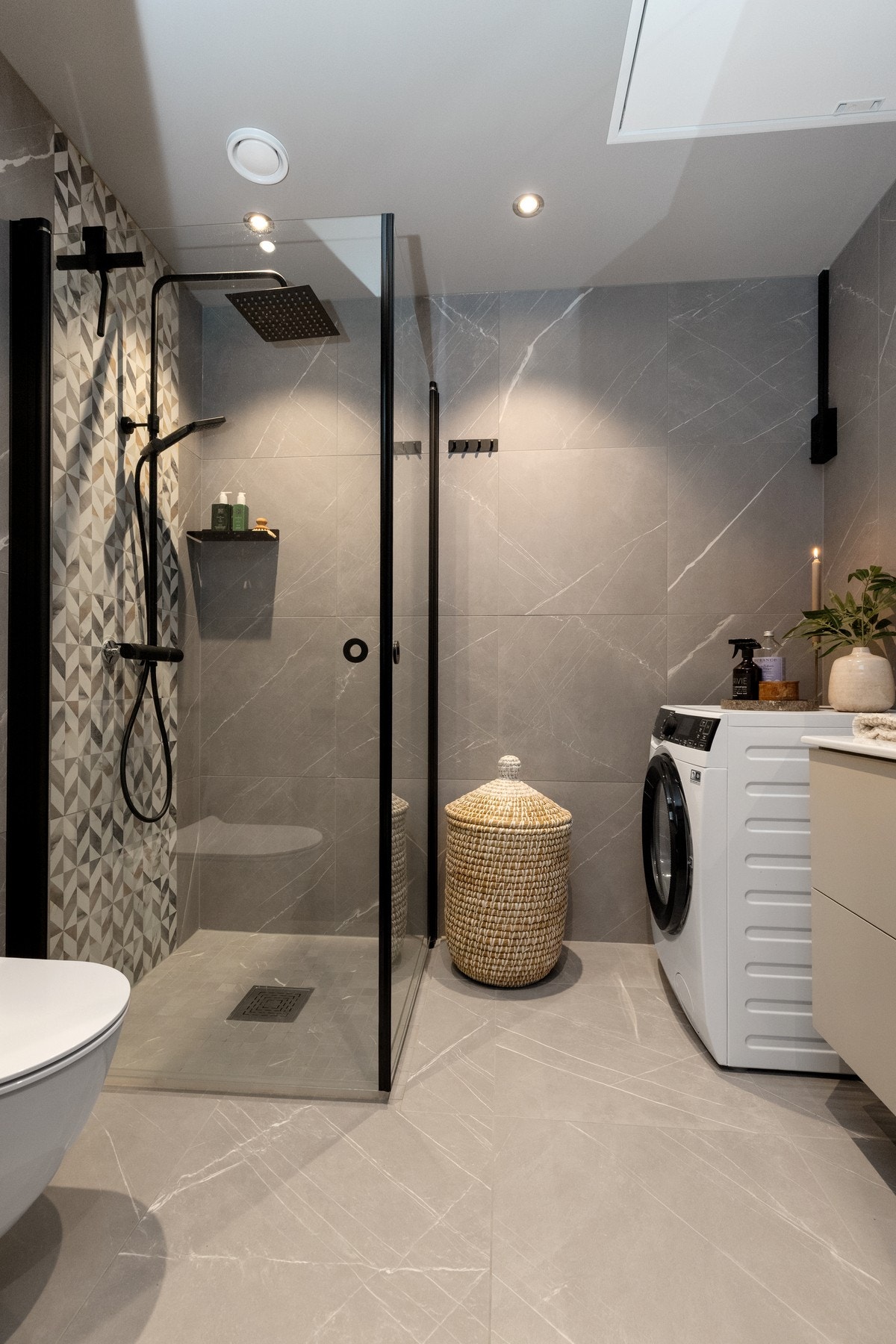 Det andre badet har også store fliser på gulv og vegg.
Dusjdører i sort profil, det samme med regnfallsdusj og hånddusj. Galleribilde