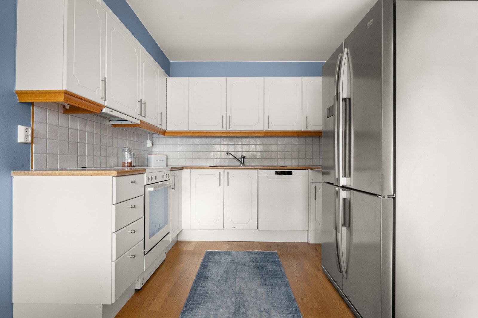 Innredningen har hvite, profilerte fronter og gyllen laminatbenkeplate med nedfelt kum i stål. Galleribilde