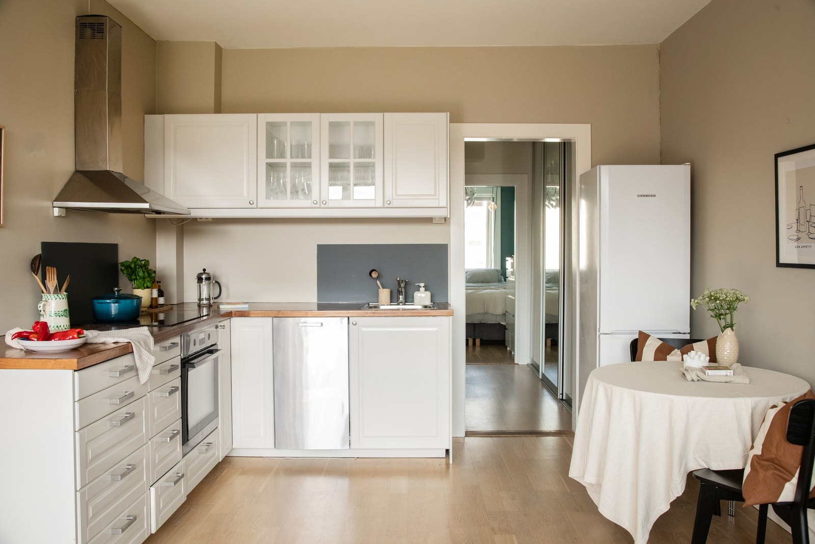 Tidløst kjøkken med benkeplate i tre som tilfører en varm og naturlig kontrast til den lyse innredningen. Galleribilde