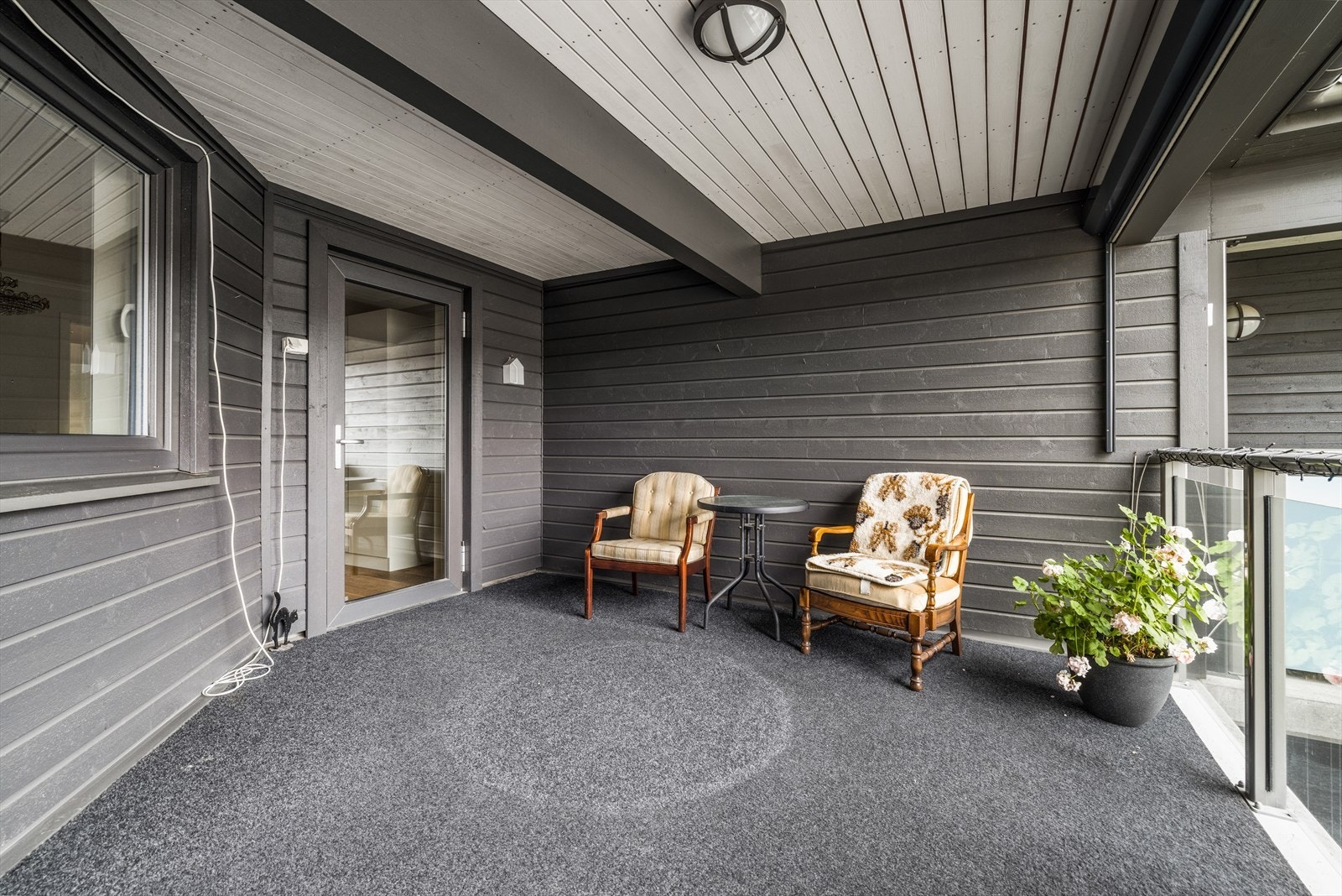 Romslig, overbygget balkong med teppe på gulv og solskjerming med fjernkontroll. Galleribilde